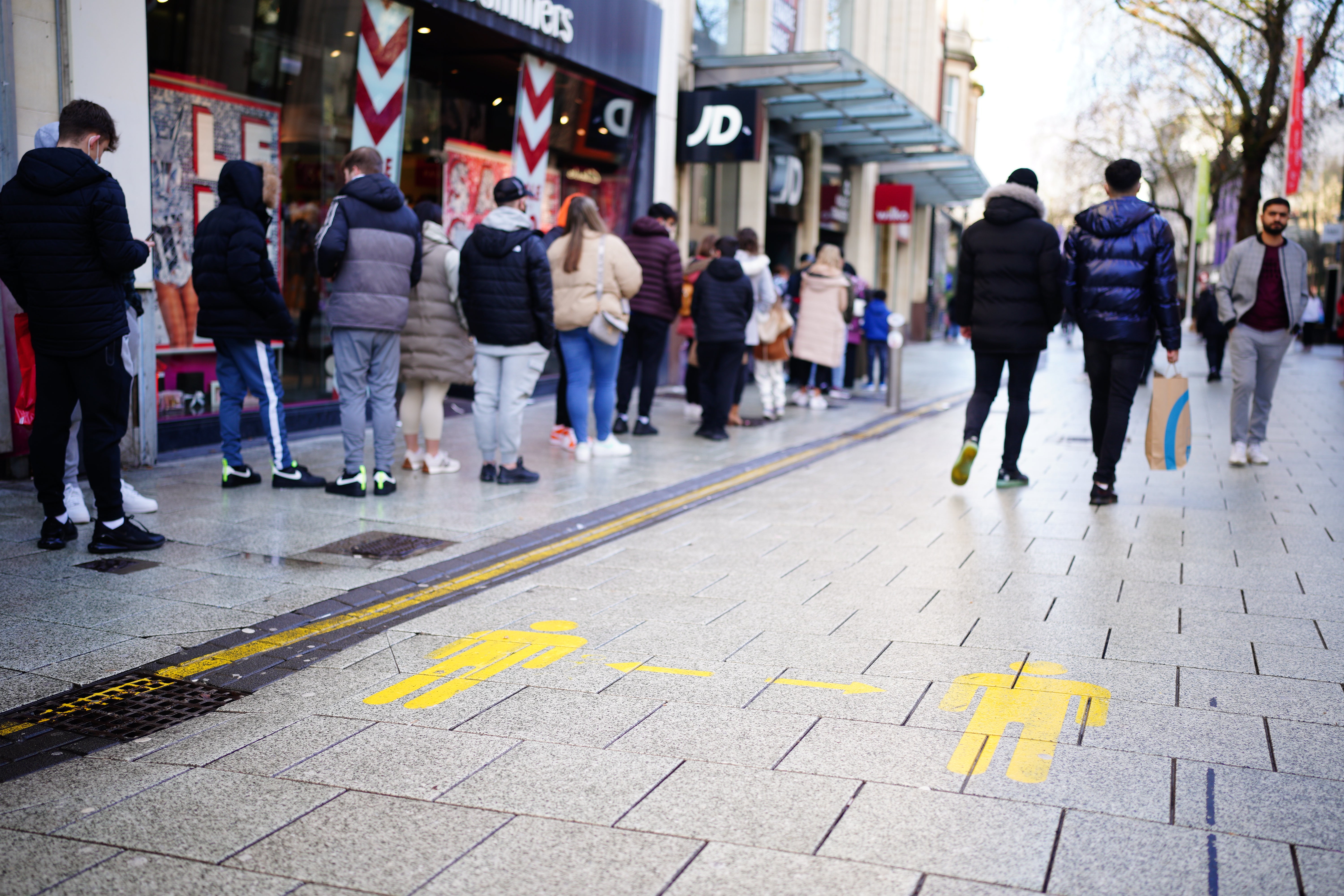 People stand in line to enter a shop in Cardiff, Wales (Ben Birchall/PA)