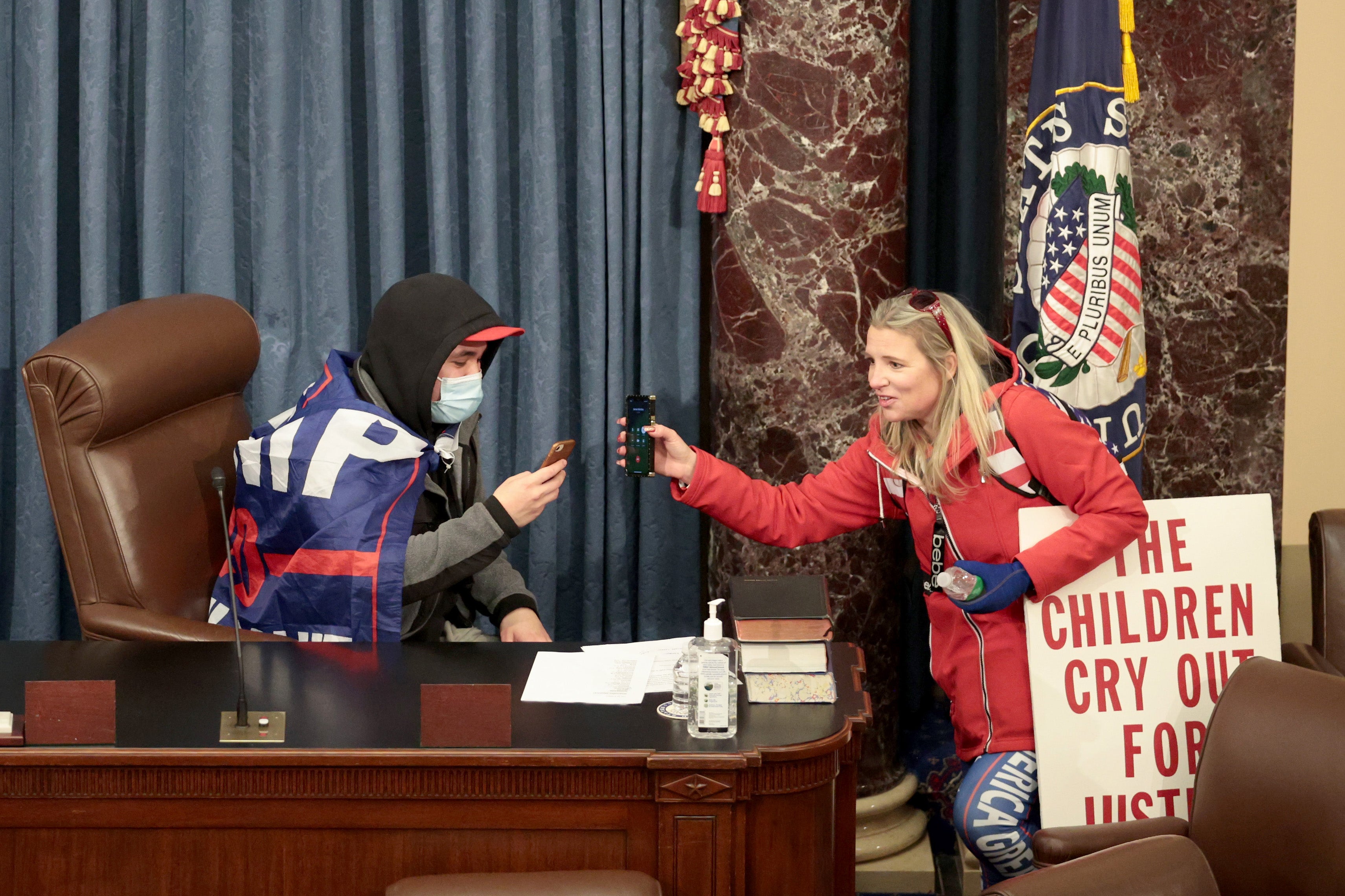 Christine Priola stands in the Senate chamber carrying a sign alluding to QAnon