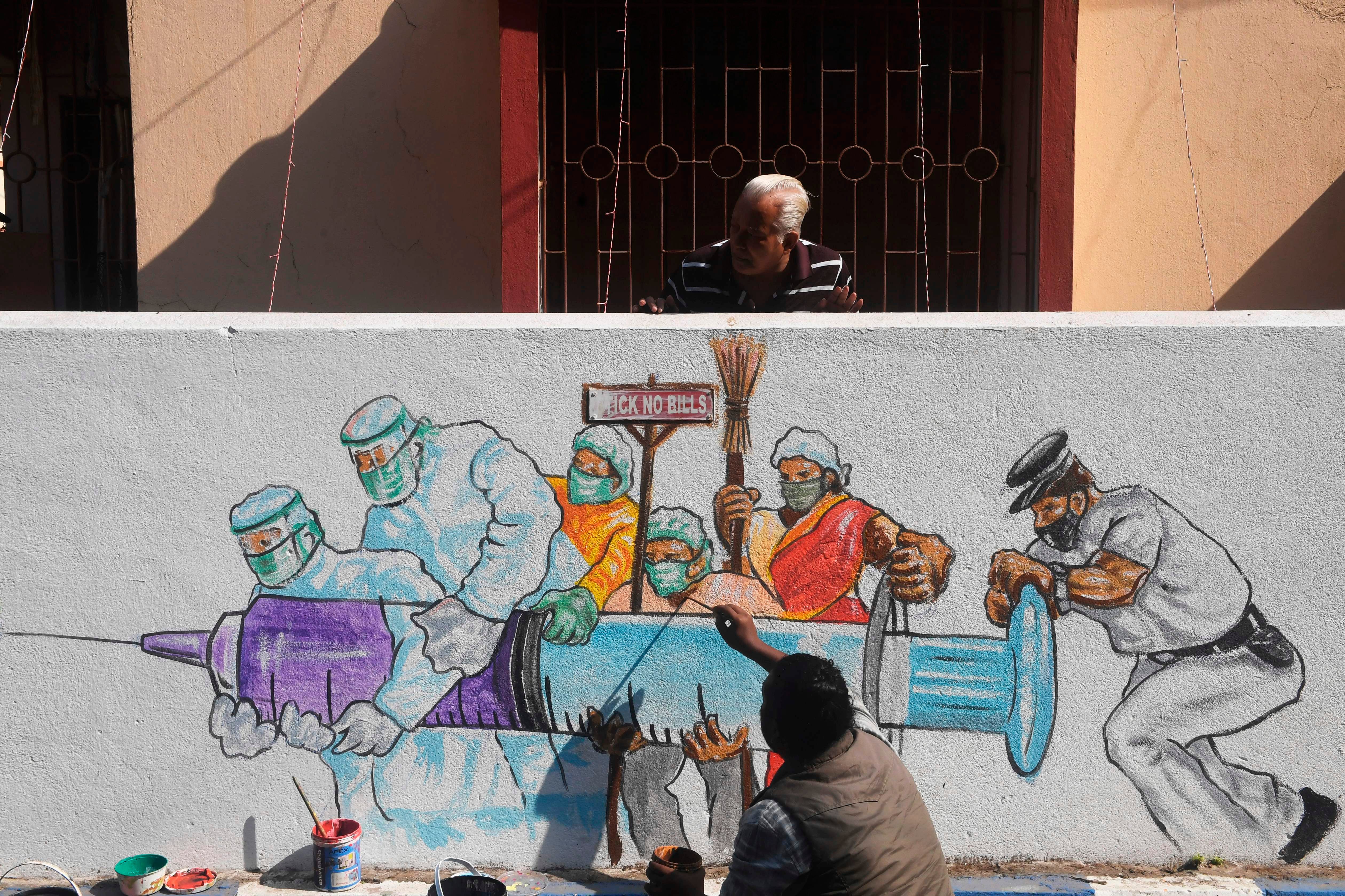 An artist gives his finishing touches to a mural depicting frontline workers carrying a Covid vaccine in Kolkata on 2 January 2021