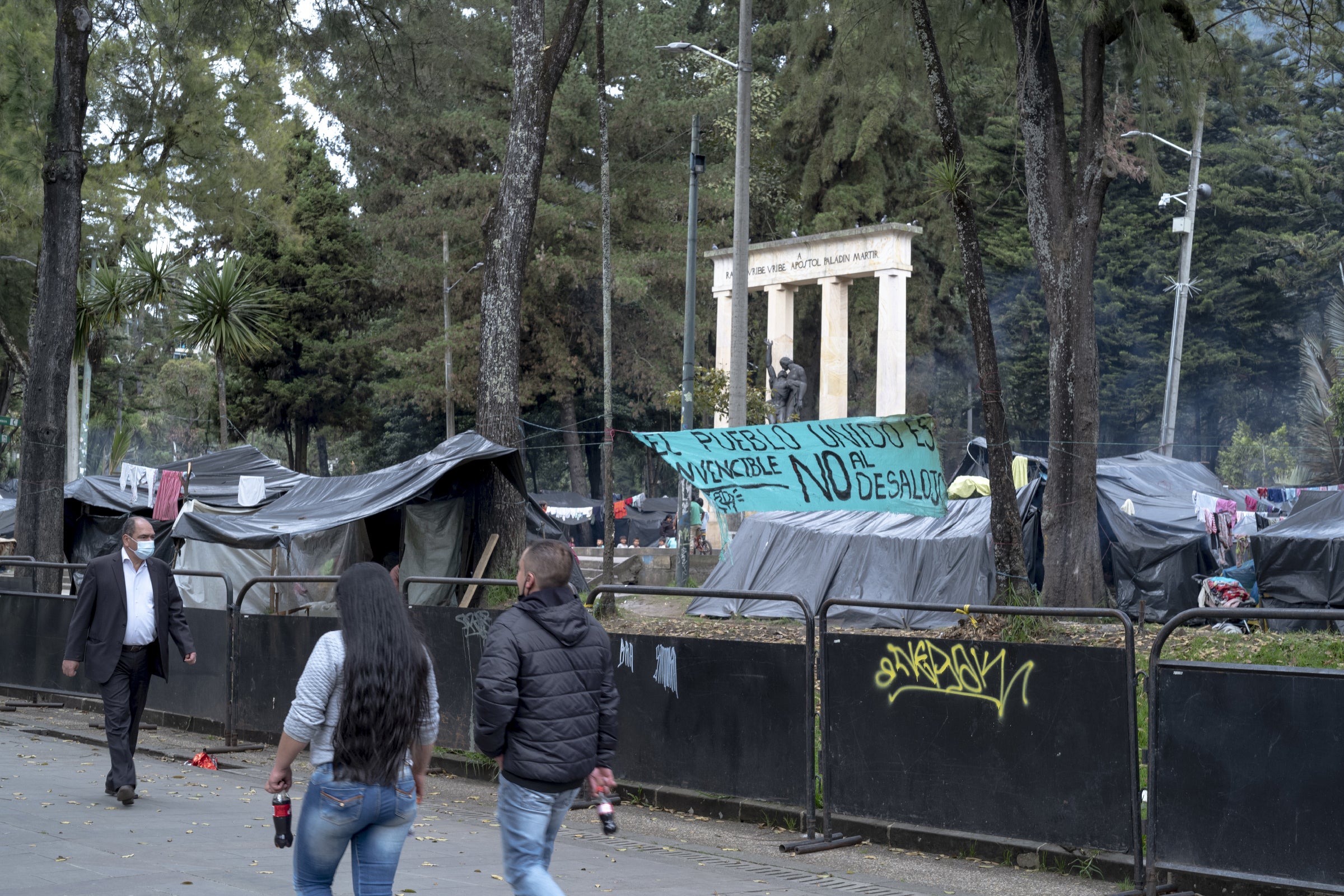 Pedestrians walk past a banner in Bogota that reads, ‘The people united are invincible. No to the eviction’