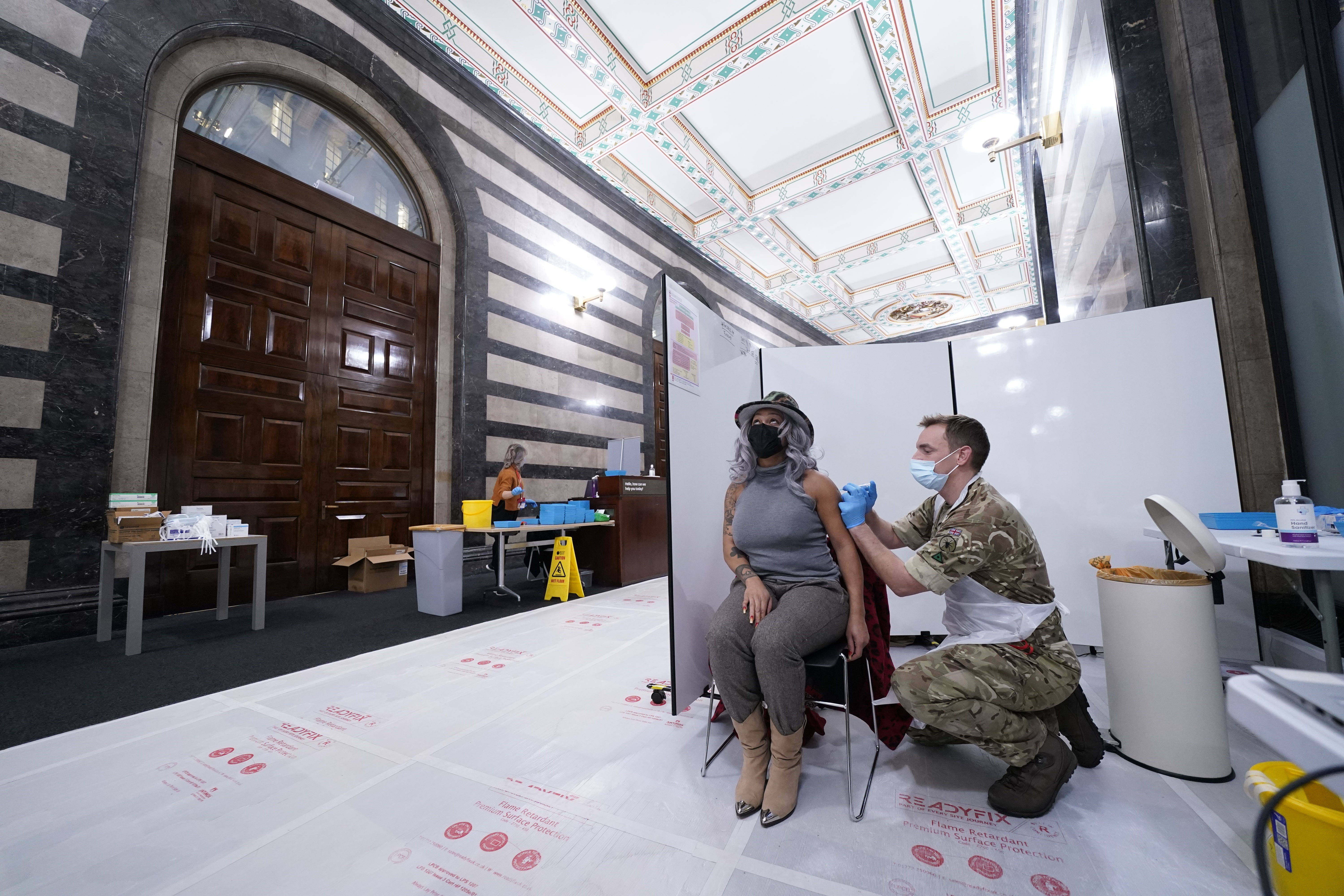 Bombardier Ian Bloomfield of the 5th Regiment Royal Artillery gives a Covid-19 vaccine to Sheila Riberio at the vaccination centre in Rates Hall, Manchester (Danny Lawson/PA)