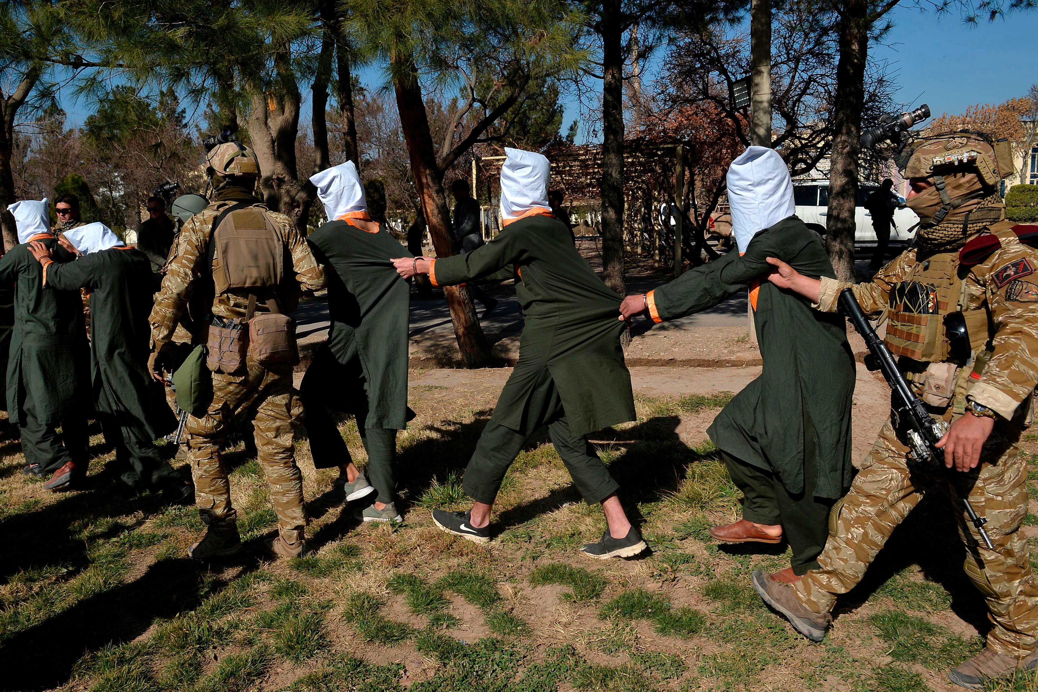 Men suspected to be Taliban fighters being chaperoned by Afghan security forces in wake of operation at National Directorate of Security headquarters in Herat in February 2021