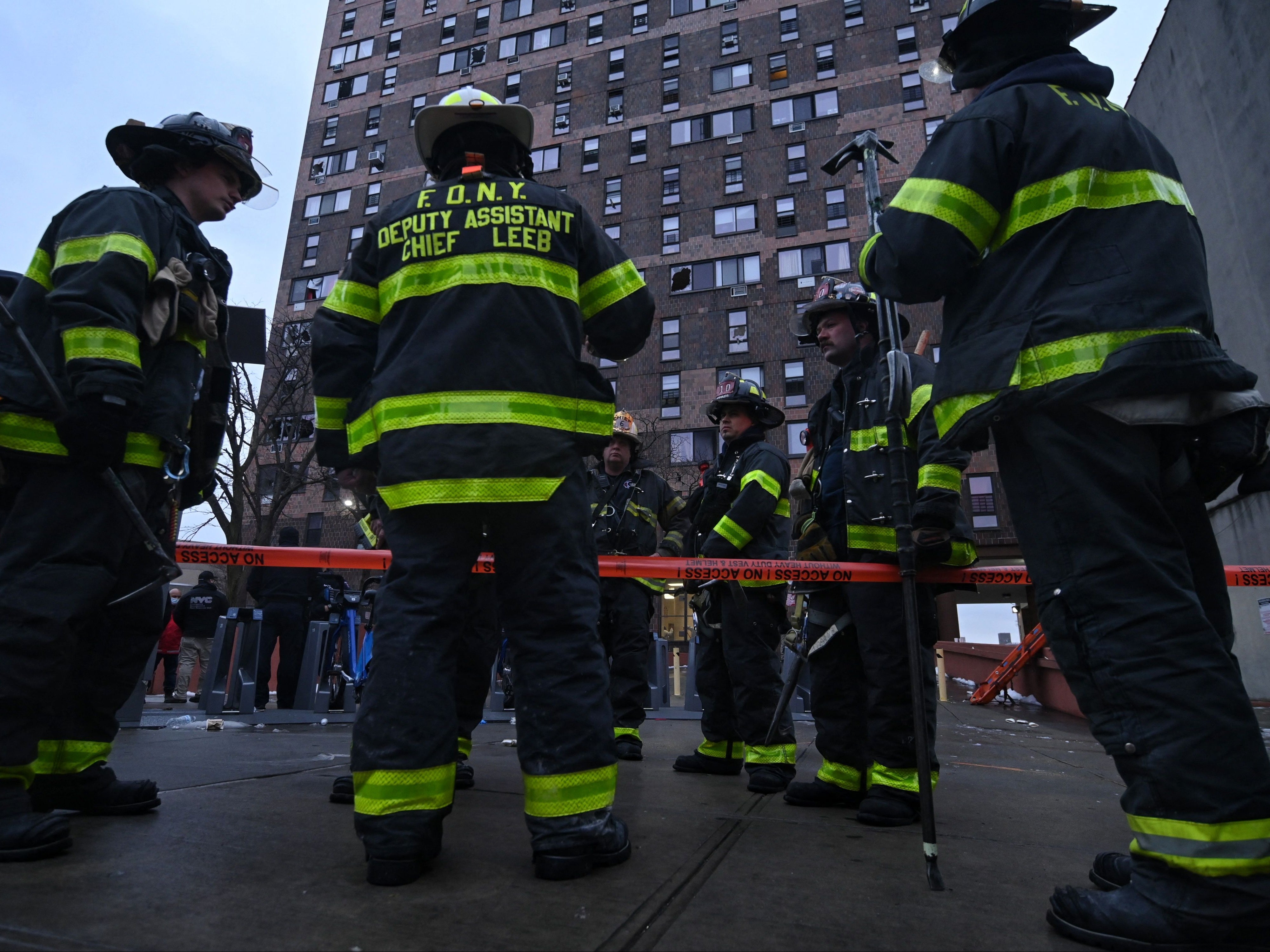 Firefighters work outside an apartment building after a fire in the Bronx, on January 9, 2022, in New York.