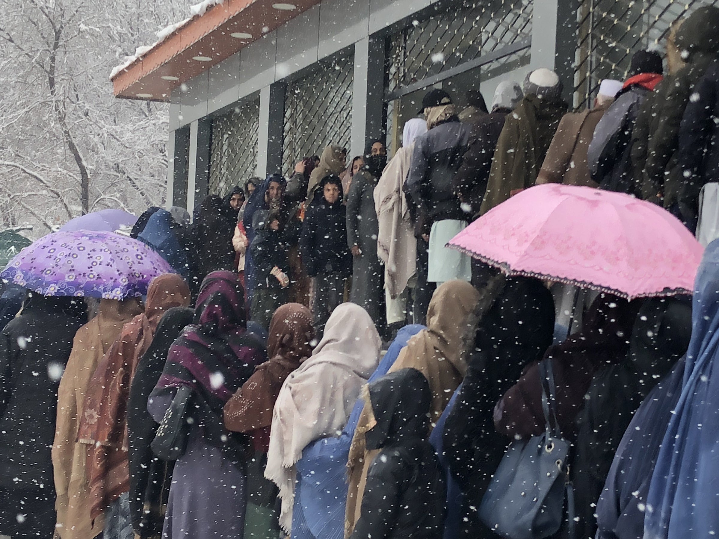 Afghan women wait in heavy snowfall for food donations from the World Food Programme