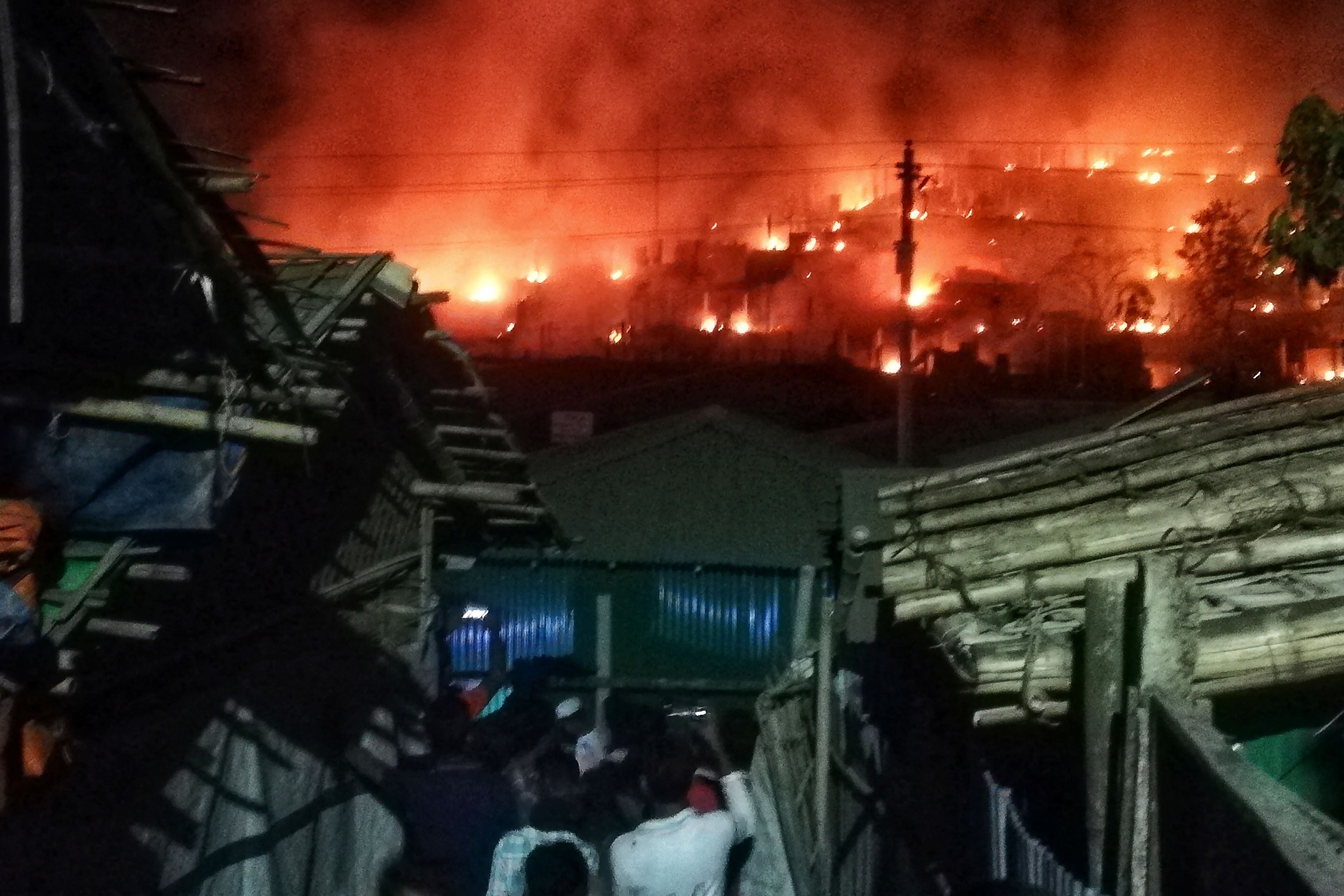 Onlookers gather as smoke and flames can be seen on a hillside after a fire broke out in a Rohingya refugee camp in Ukhia on 9 January