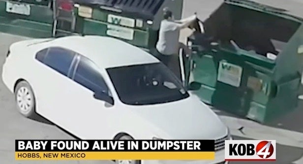 Woman is seen tossing a black trash bag into a dumpster containing a baby