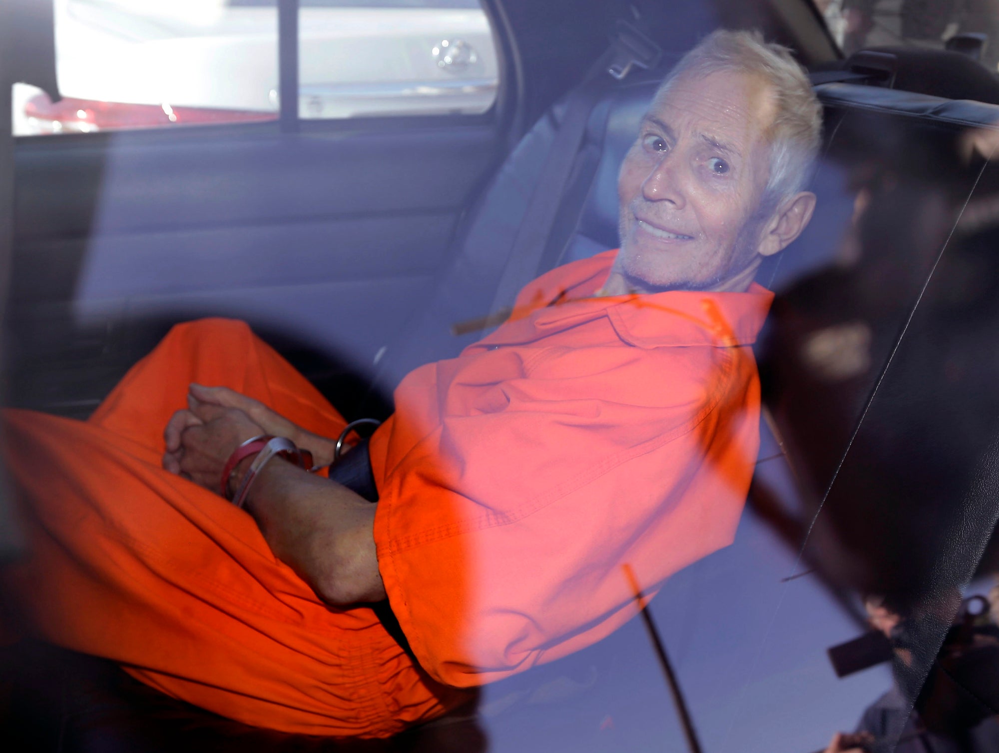 Robert Durst is pictured in 2015 smiling in prison garb after being arrested for Susan Berman’s murder