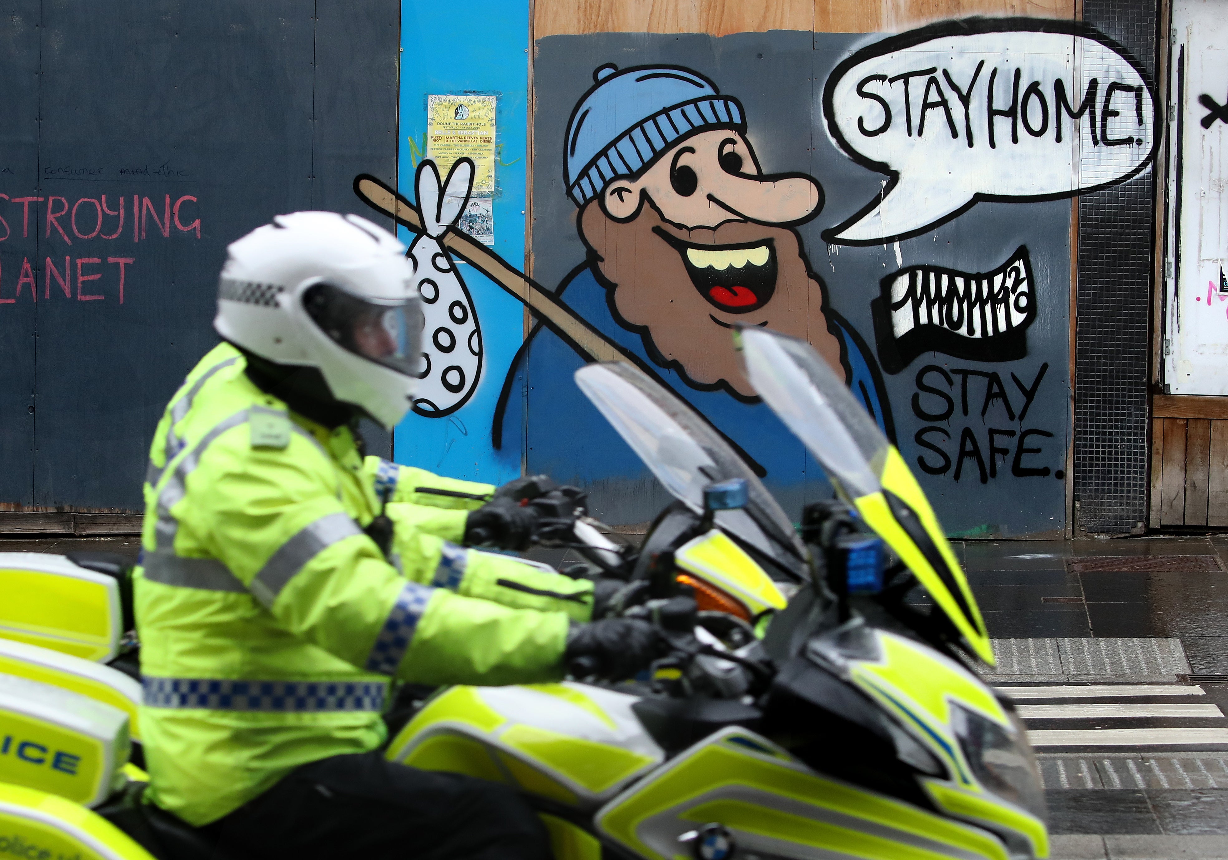 A police motorcyclist passes coronavirus related graffiti on a wall in Glasgow (Andrew Milligan/PA)