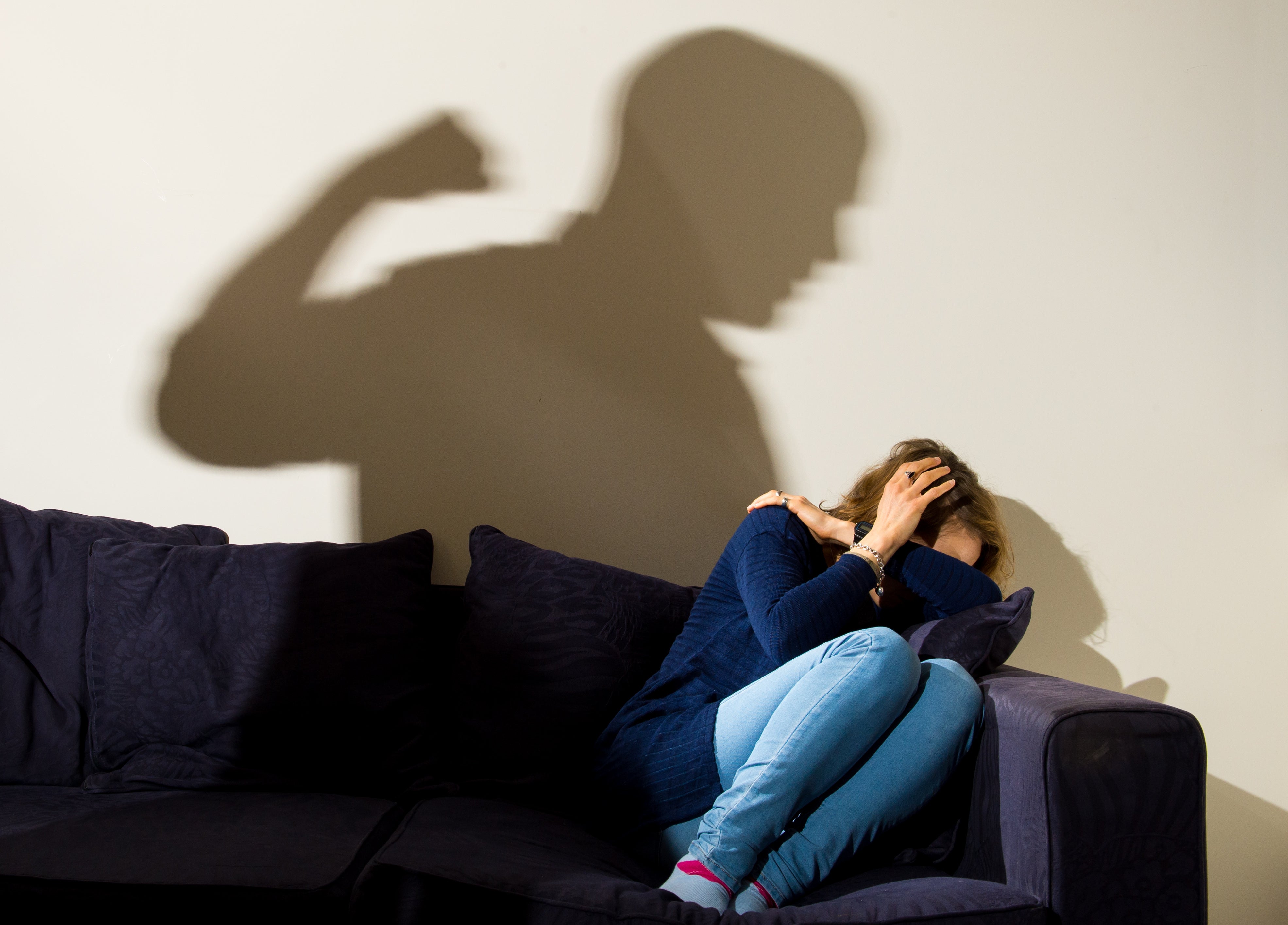 A shadow of a man with a clenched fist as a woman cowers in the corner (picture posed by model) (Dominic Lipinski/PA)