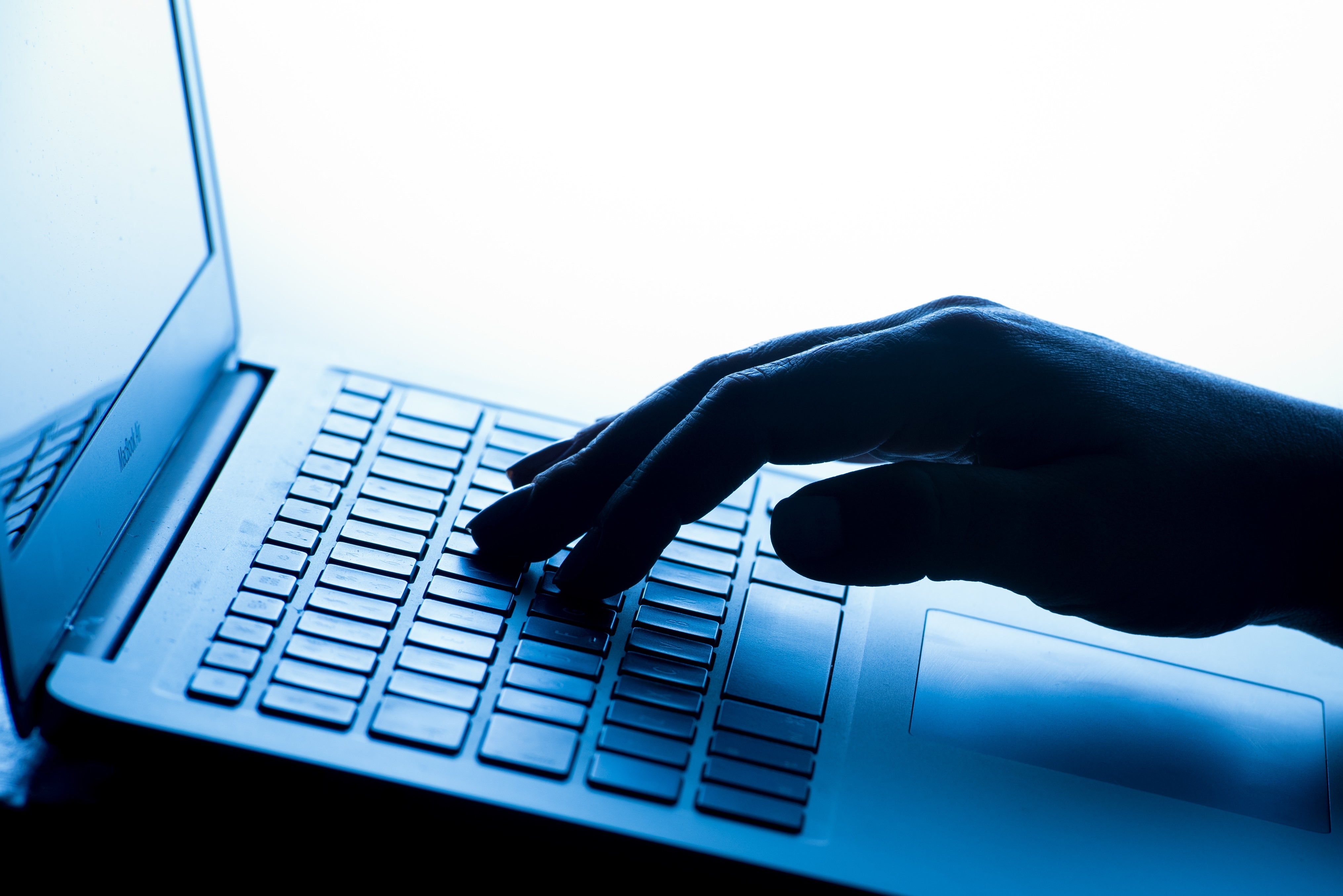 A woman’s hand presses a key of a laptop keyboard.