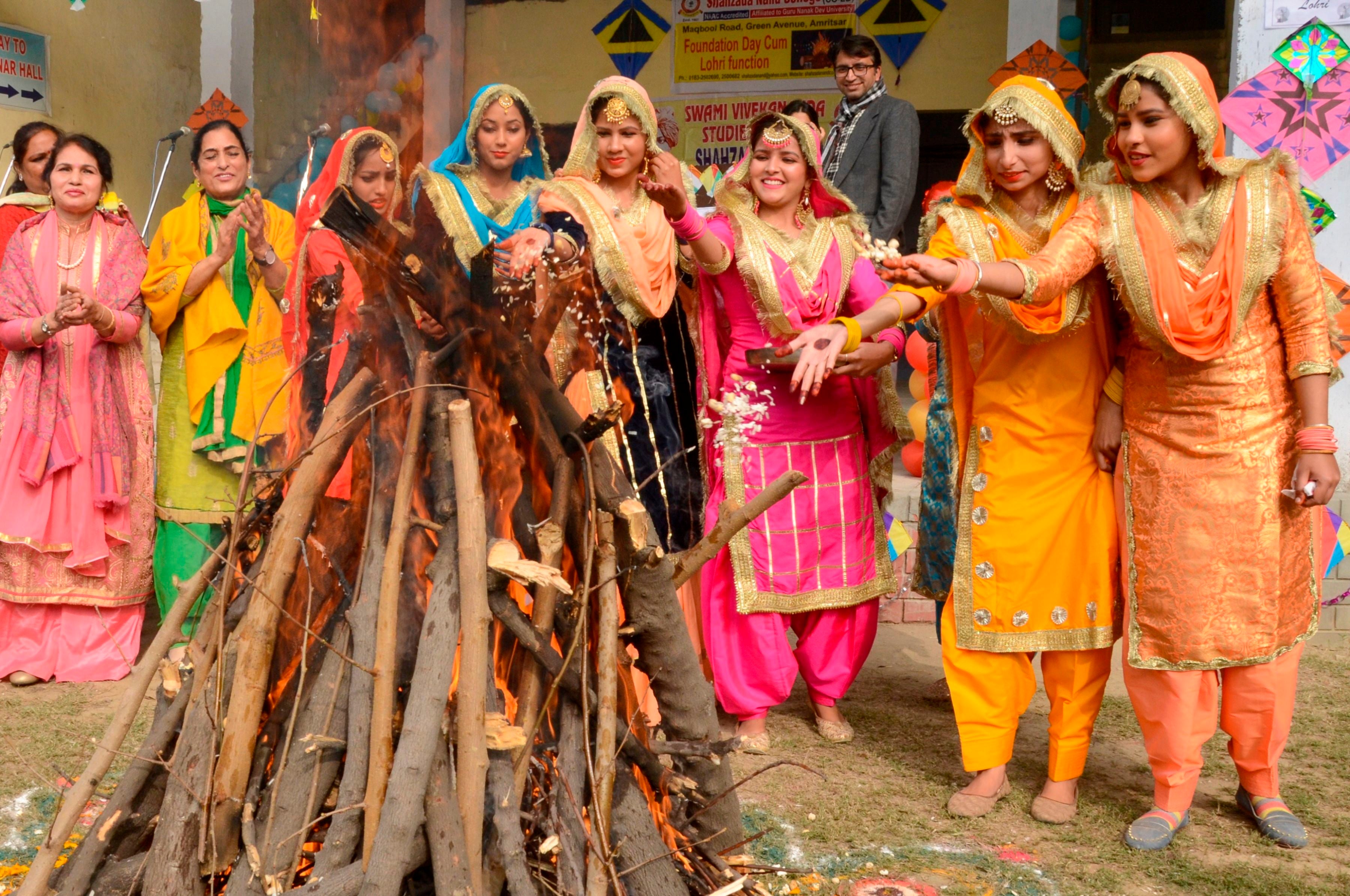 Students wearing traditional Punjabi outfits perform a ritual around a bonfire to celebrate Lohri