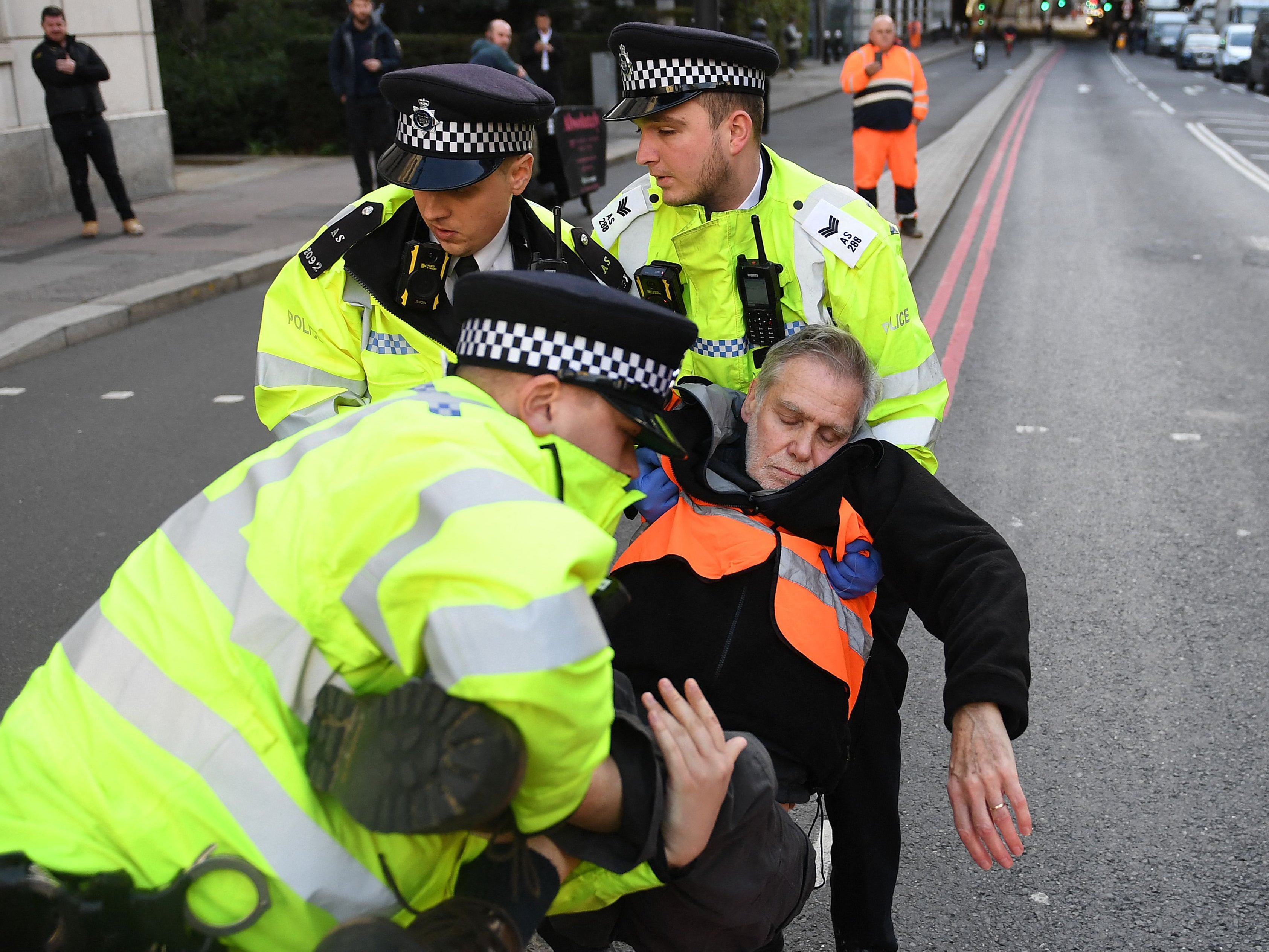 Police officers remove an Insulate Britain member as protesters block a street in central London