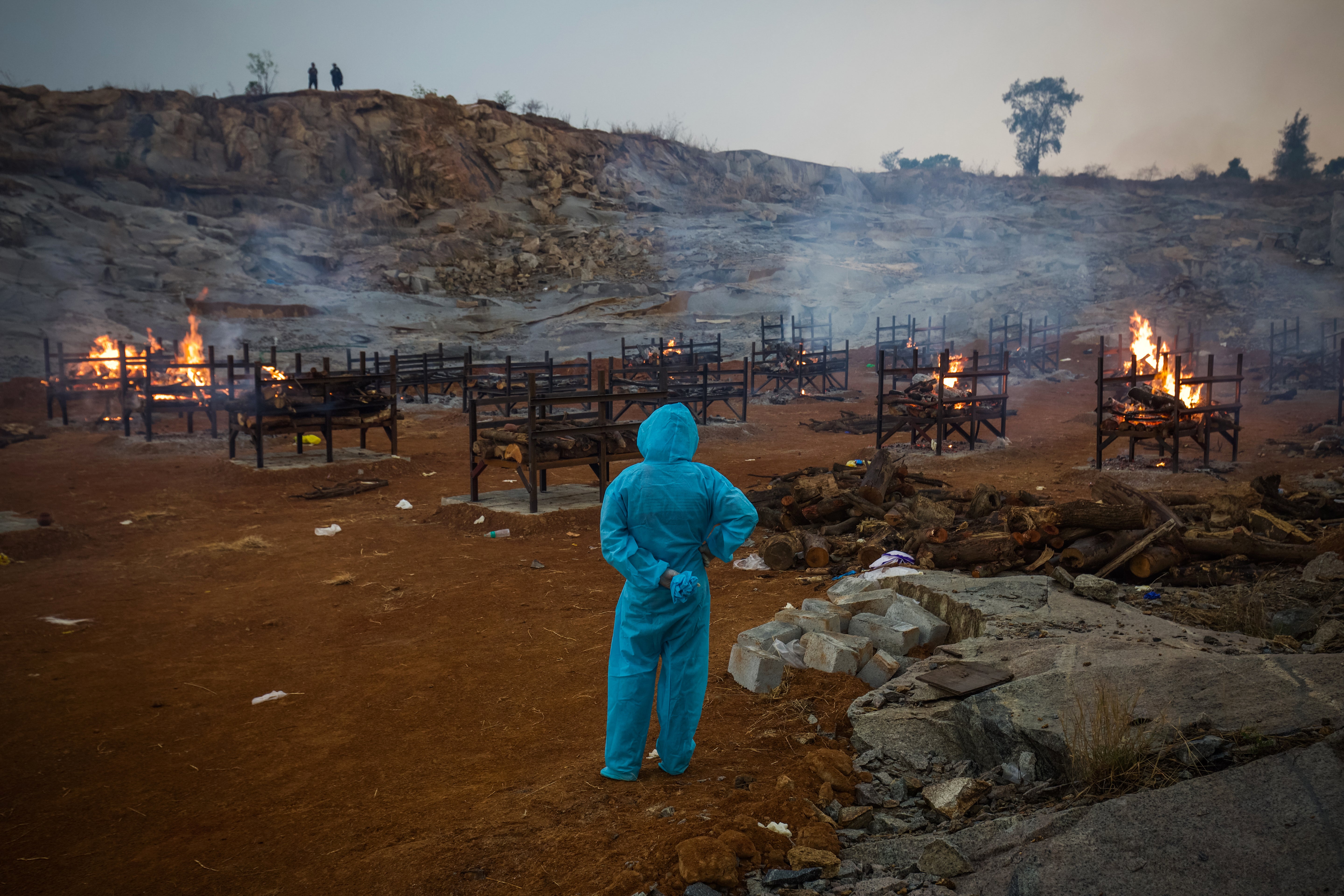 File photo: A man wearing PPE (Personal Protective Equipment) watches mass cremations during the second wave of coronavirus pandemic on 30 April 2021 in Bengaluru, India