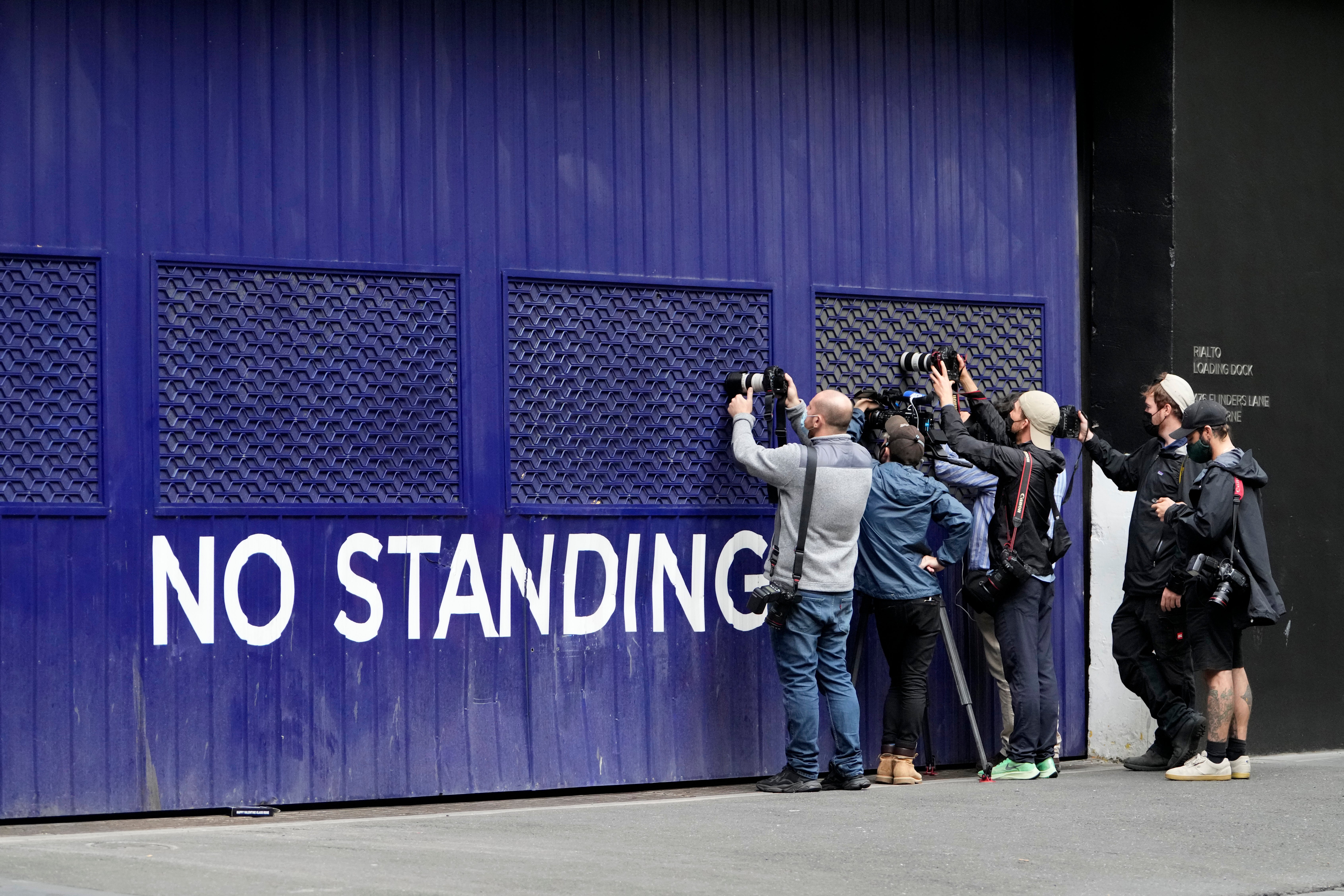 Photographers attempt to take pictures outside a building that houses the office of Novak Djokovic’s lawyers (Mark Baker/AP)