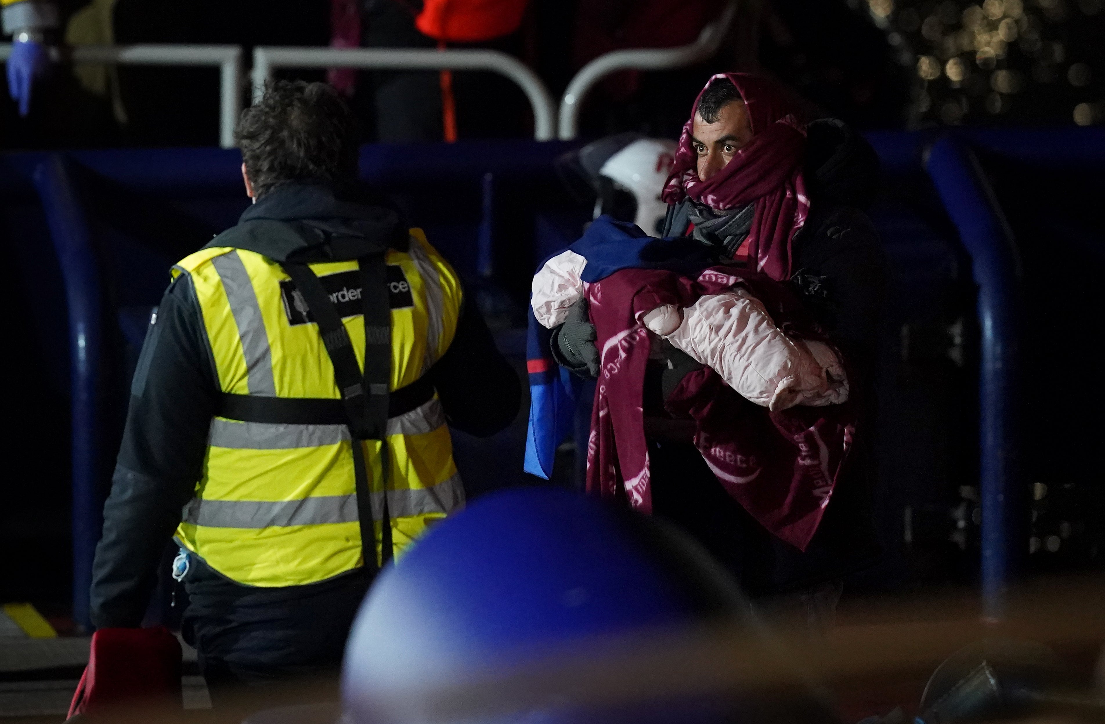 A man carries a baby as a group of people thought to be migrants are brought in to Dover, Kent, after being rescued by the RNLI following a small boat incident in the Channel (Gareth Fuller/PA)