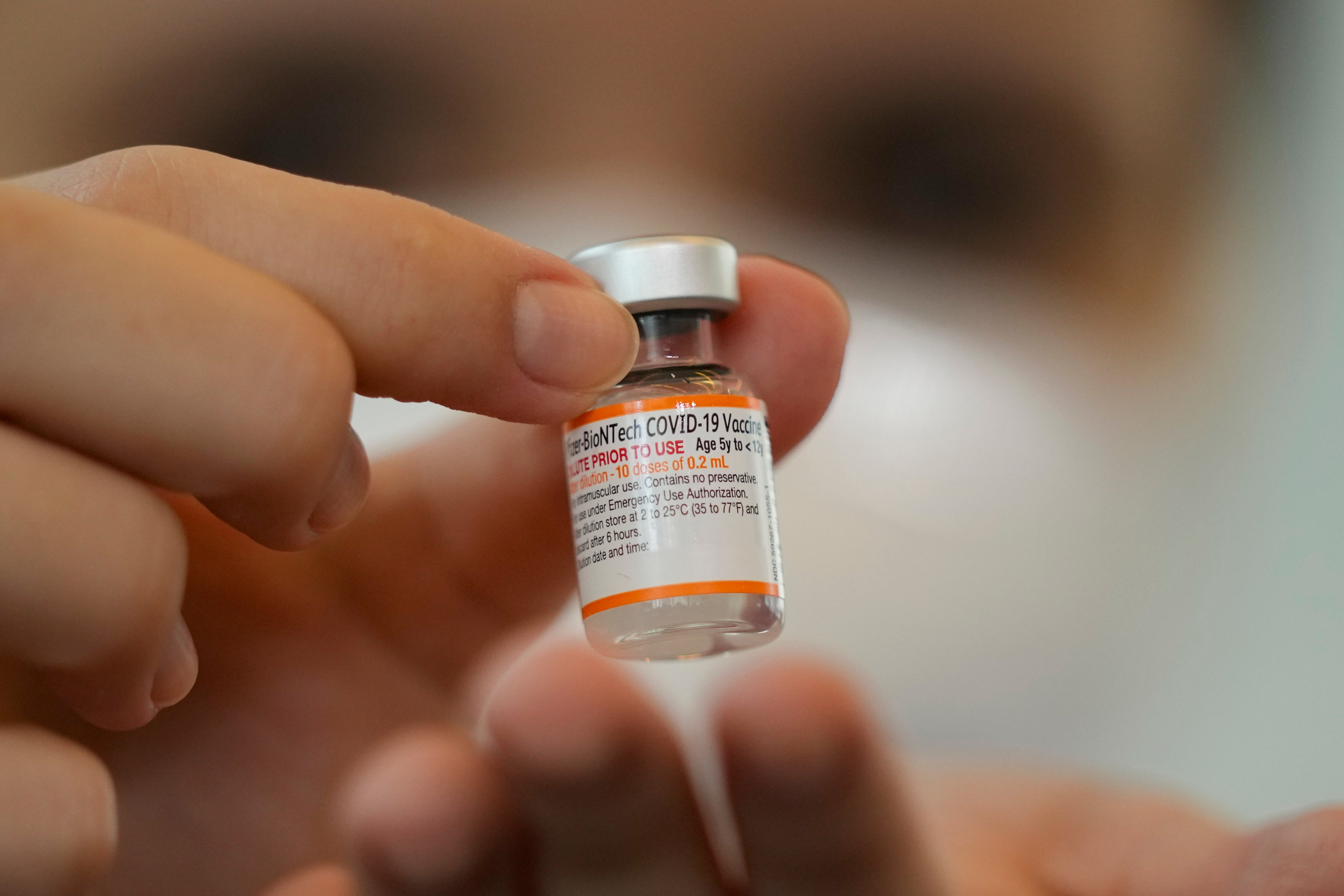 A health worker holds a vial of the Pfizer vaccine for COVID-19