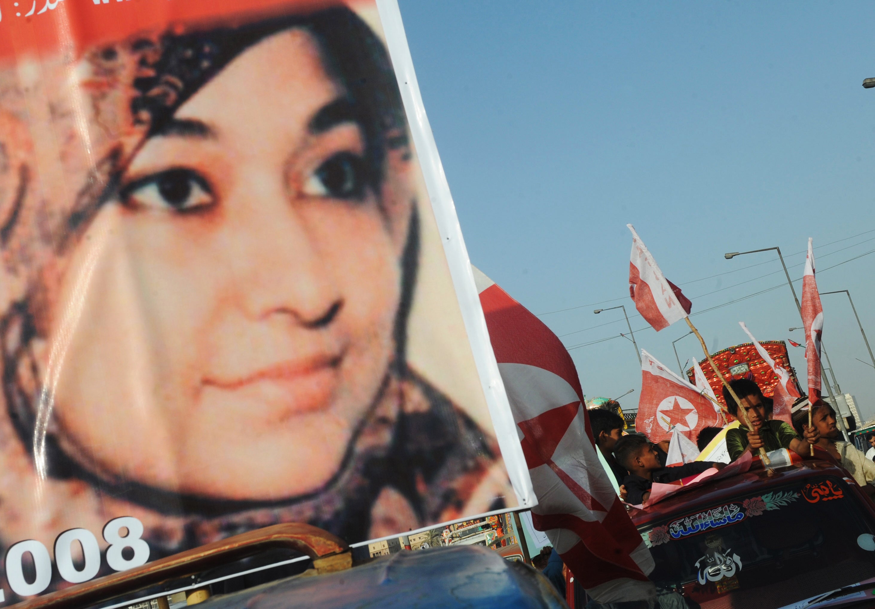 Supporters of US-detained Pakistani woman Aafia Siddiqui carry flags and placards with her portrait during an anti-US demonstration in Karachi on 28 March 2010