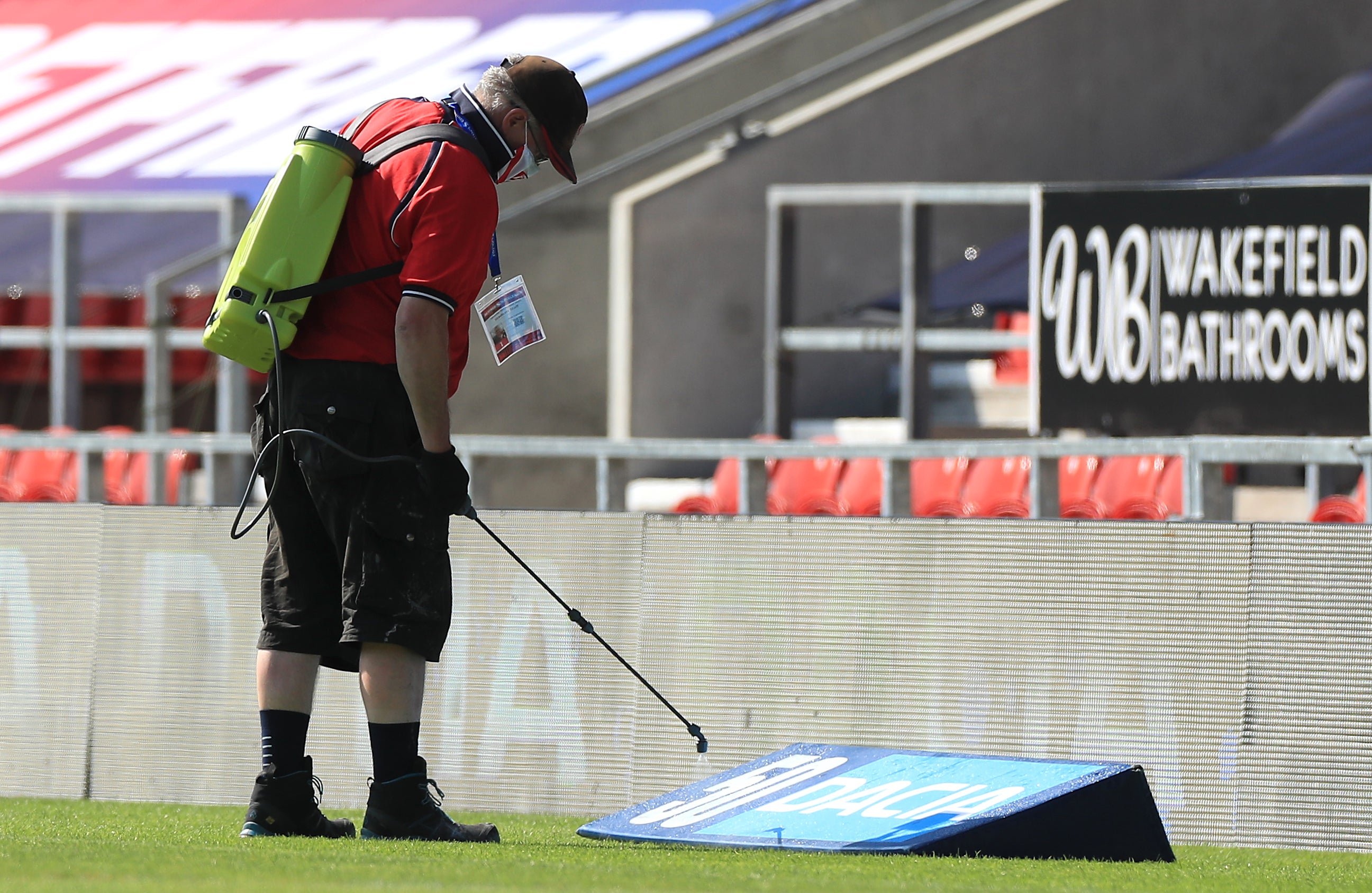 A ground staff member disinfects the area around the pitch before the Betfred Super League match at The Totally Wicked Stadium, St Helens.