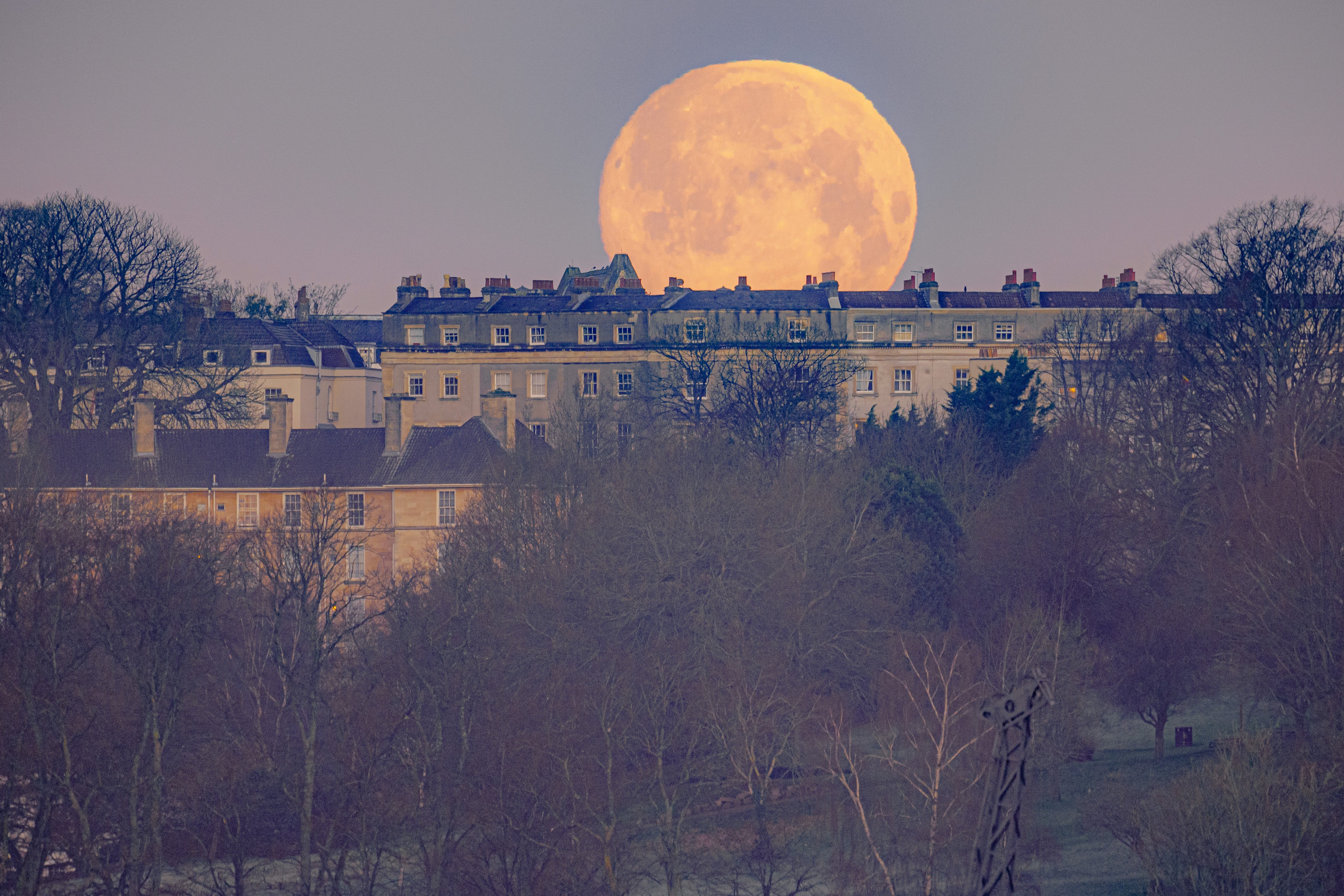 The moon appears behind houses in Bristol (Ben Birchall/PA)