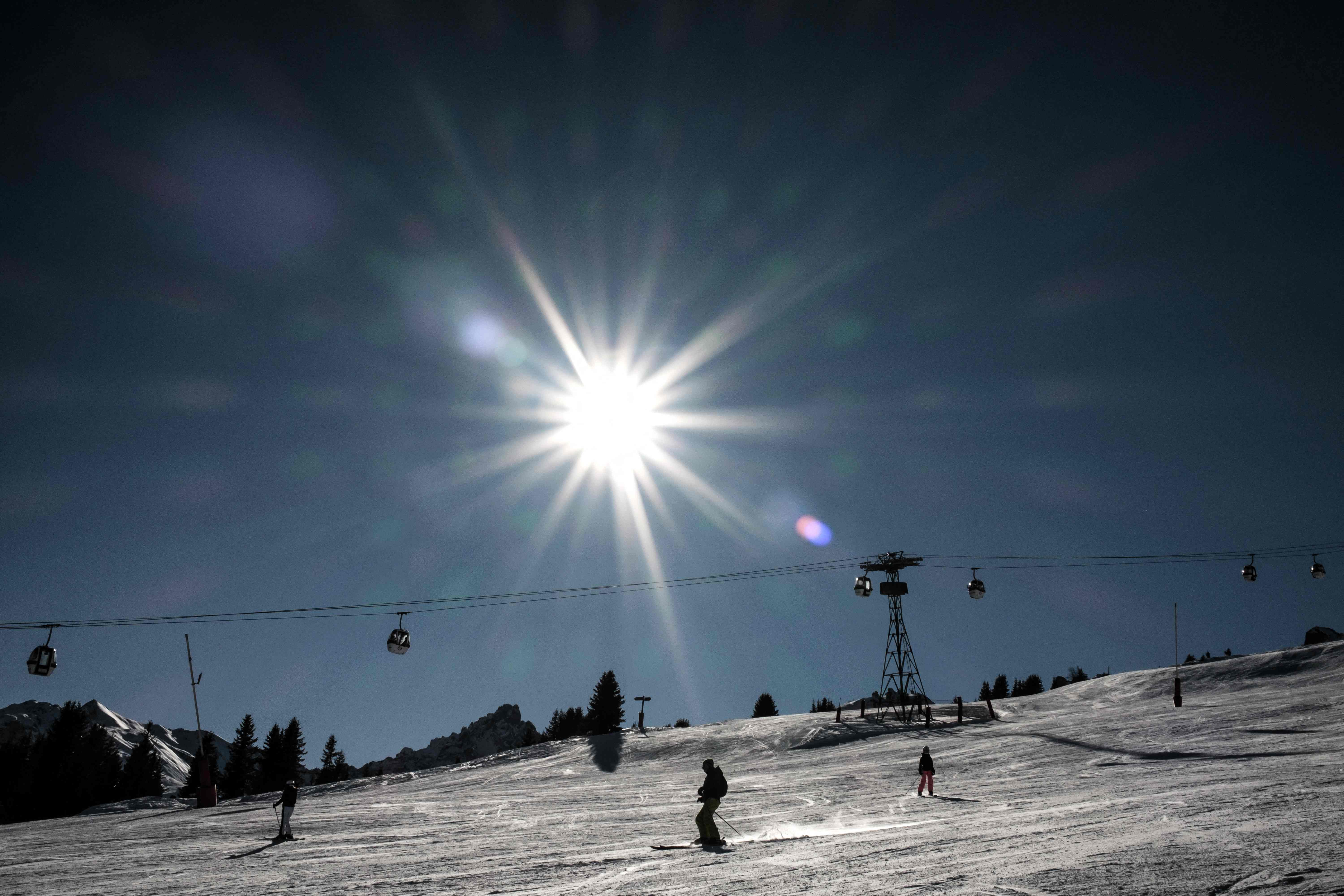 Skiers ride down a slope in the French Alps