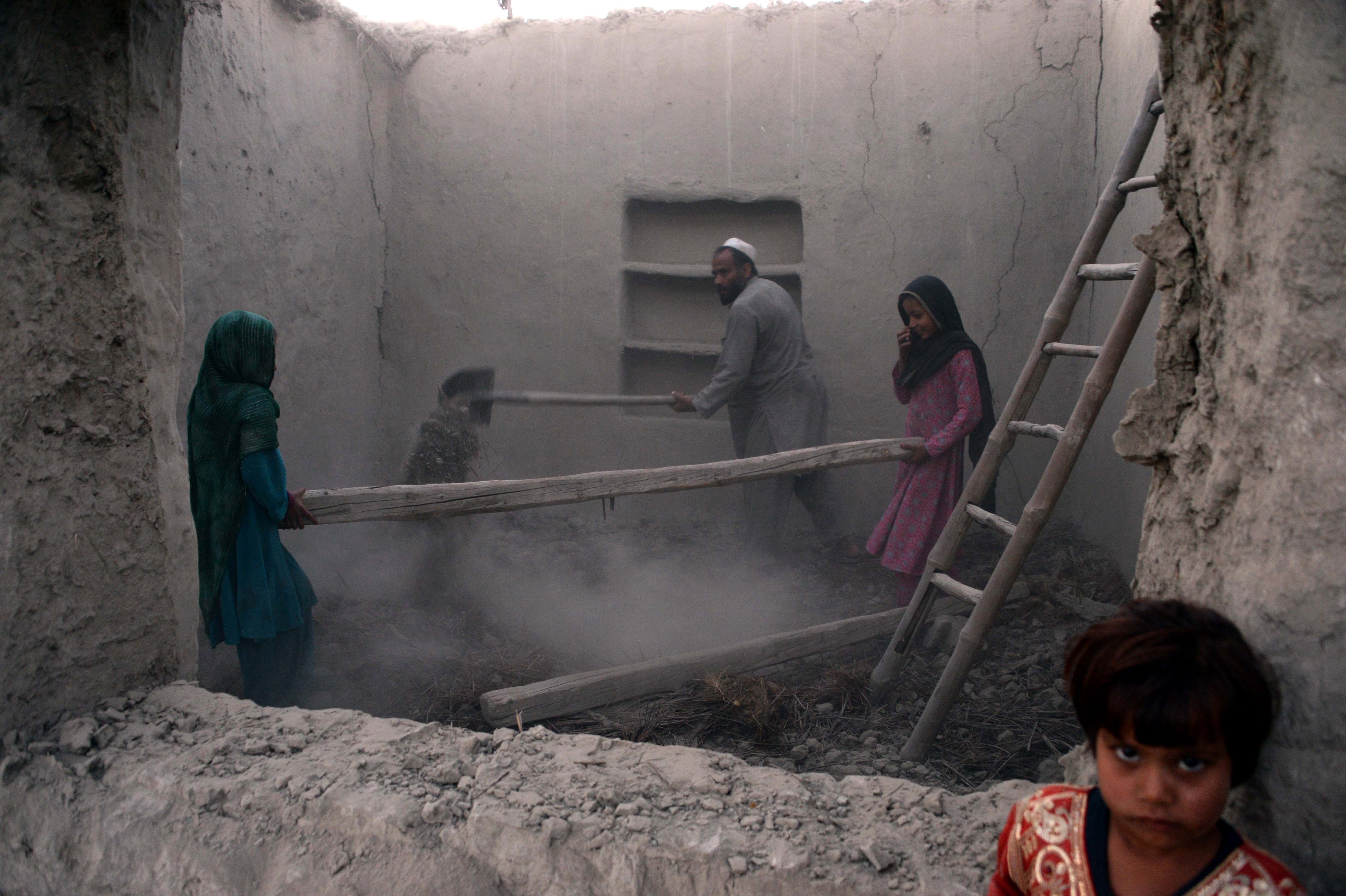 A family clears rubble from their house after it was damaged by an earthquake in the Behsud district of Nangarhar Province on 28 October 2015