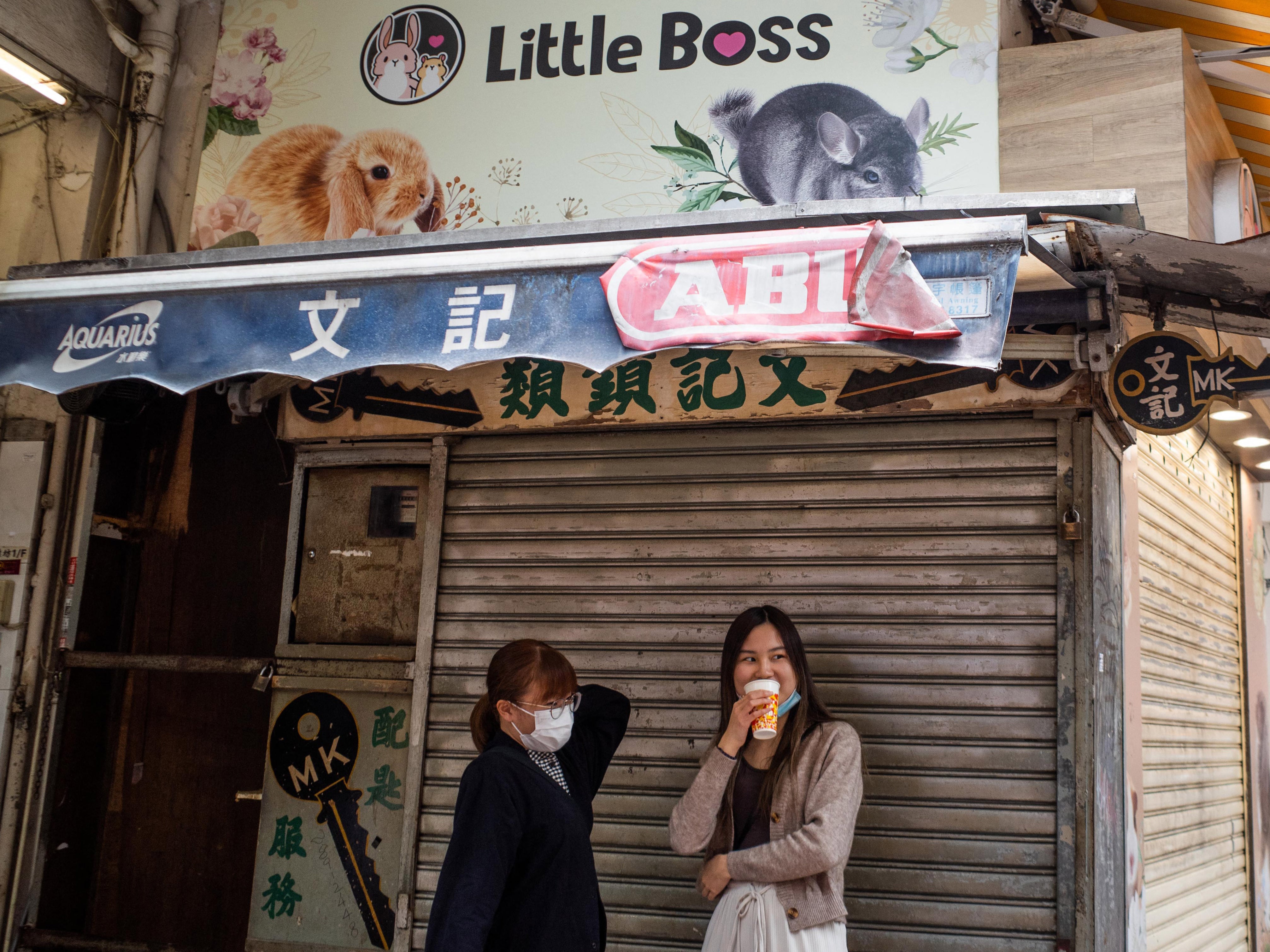 People stand under a banner for a pet shop where an employee and a customer later tested positive for Covid-19 after handling hamsters