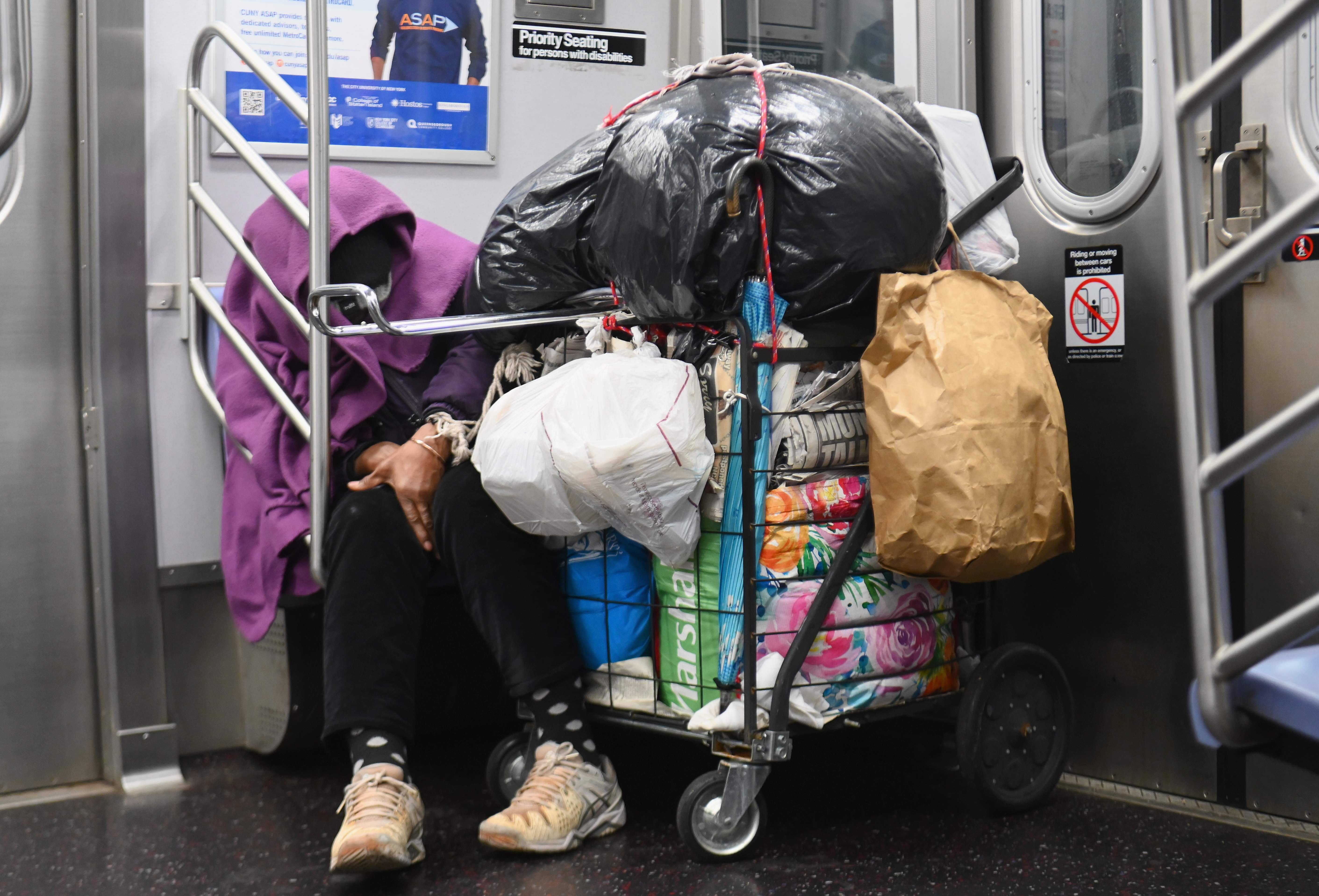 A homeless person sleeps in a subway train in New York City