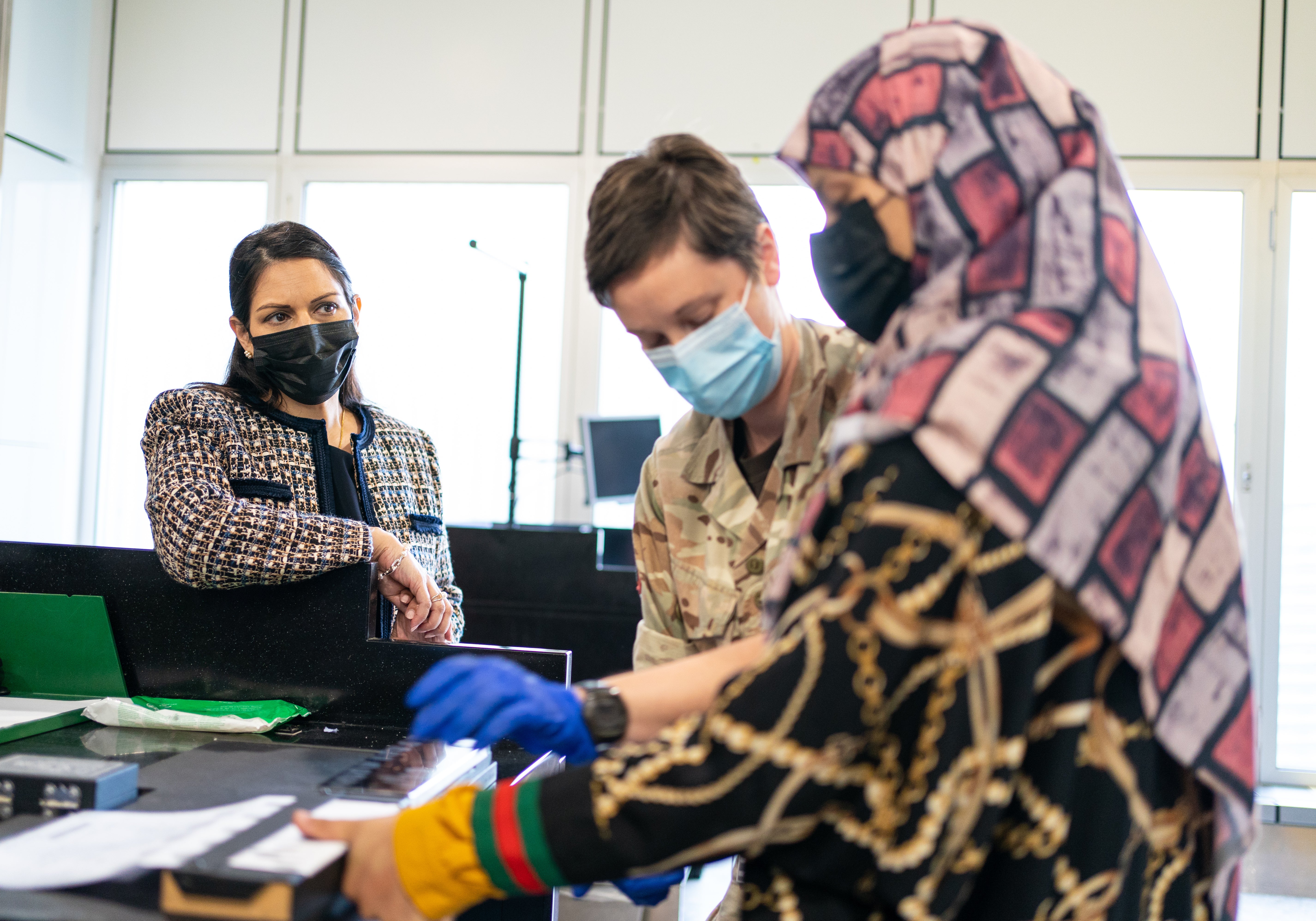 Home secretary Priti Patel watches as a refugee has her fingerprints taken after arriving from Afghanistan on an evacuation flight