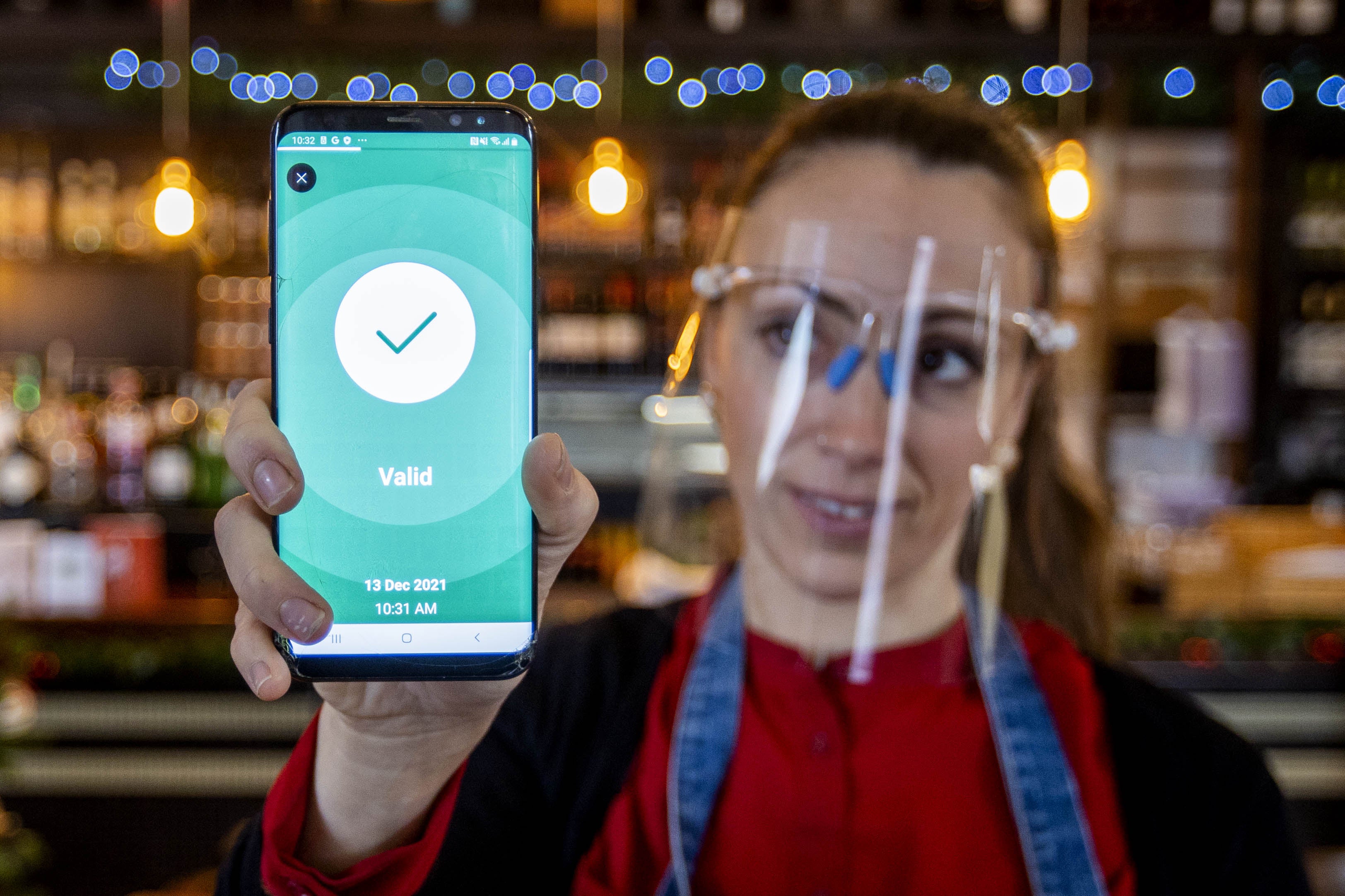 Anabela Monteiro at The Belmont Bar and Bistro in Belfast holds a customer’s scanned digital Health & Social Care Northern Ireland (HSC NI) Covid certificate (Liam McBurney/PA)