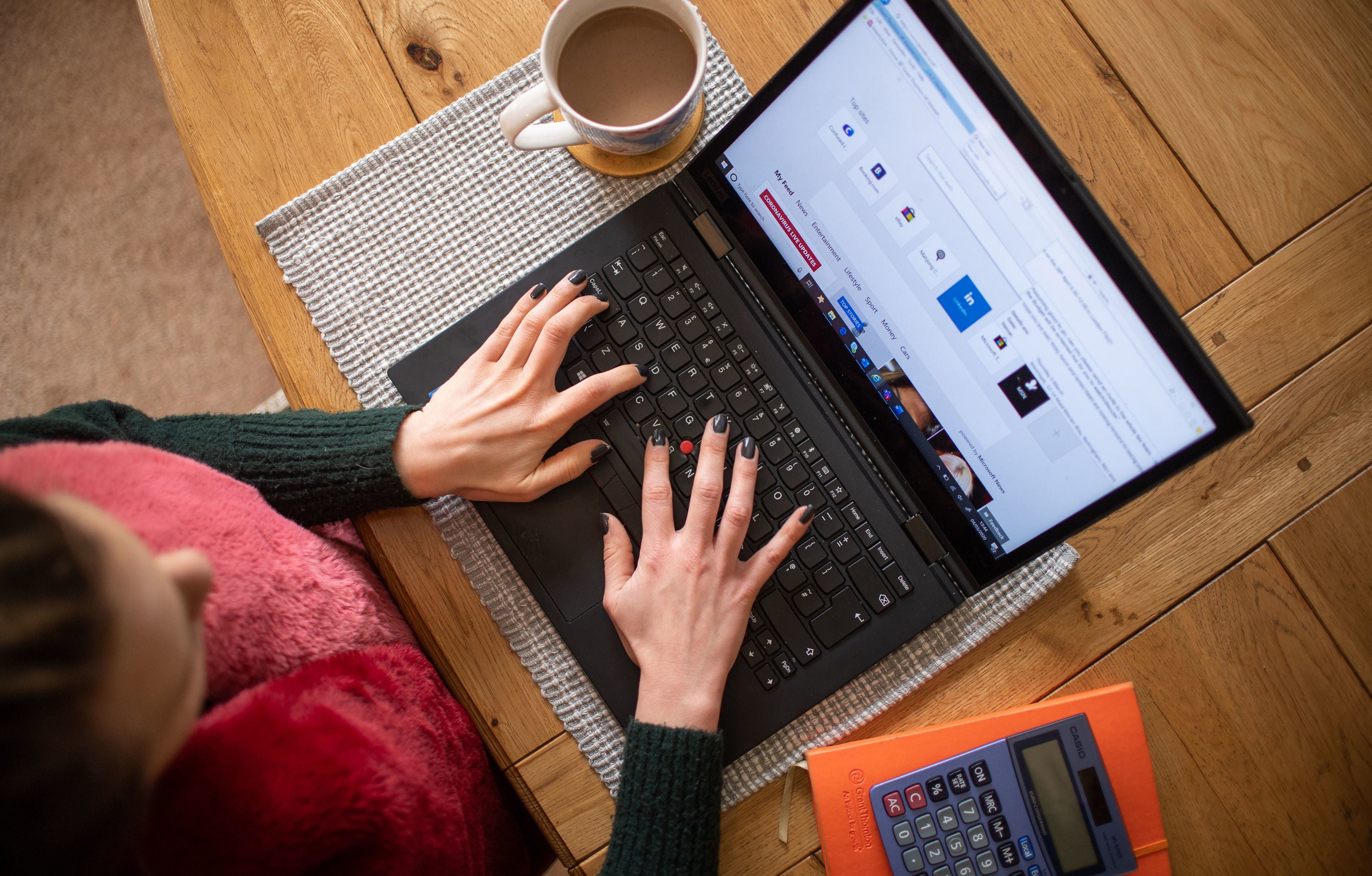 A woman using a laptop on a dining room table set up as a remote office (Joe Giddens/PA)