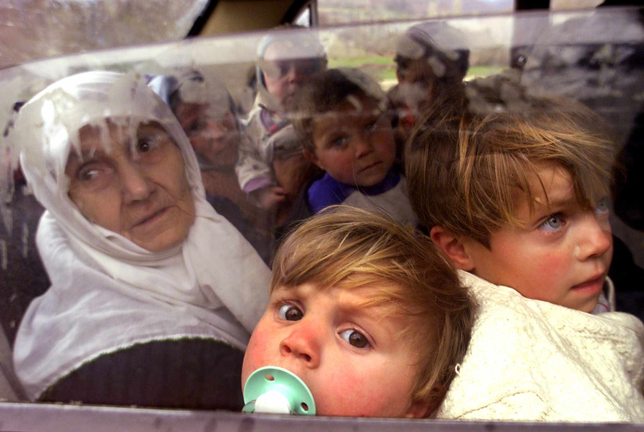 Ethnic Albanian refugees from Kosovo peer out of a small car as they cross the border from Yugoslavia into Macedonia at Blace, 25 km north of Macedonia’s capital, Skopje