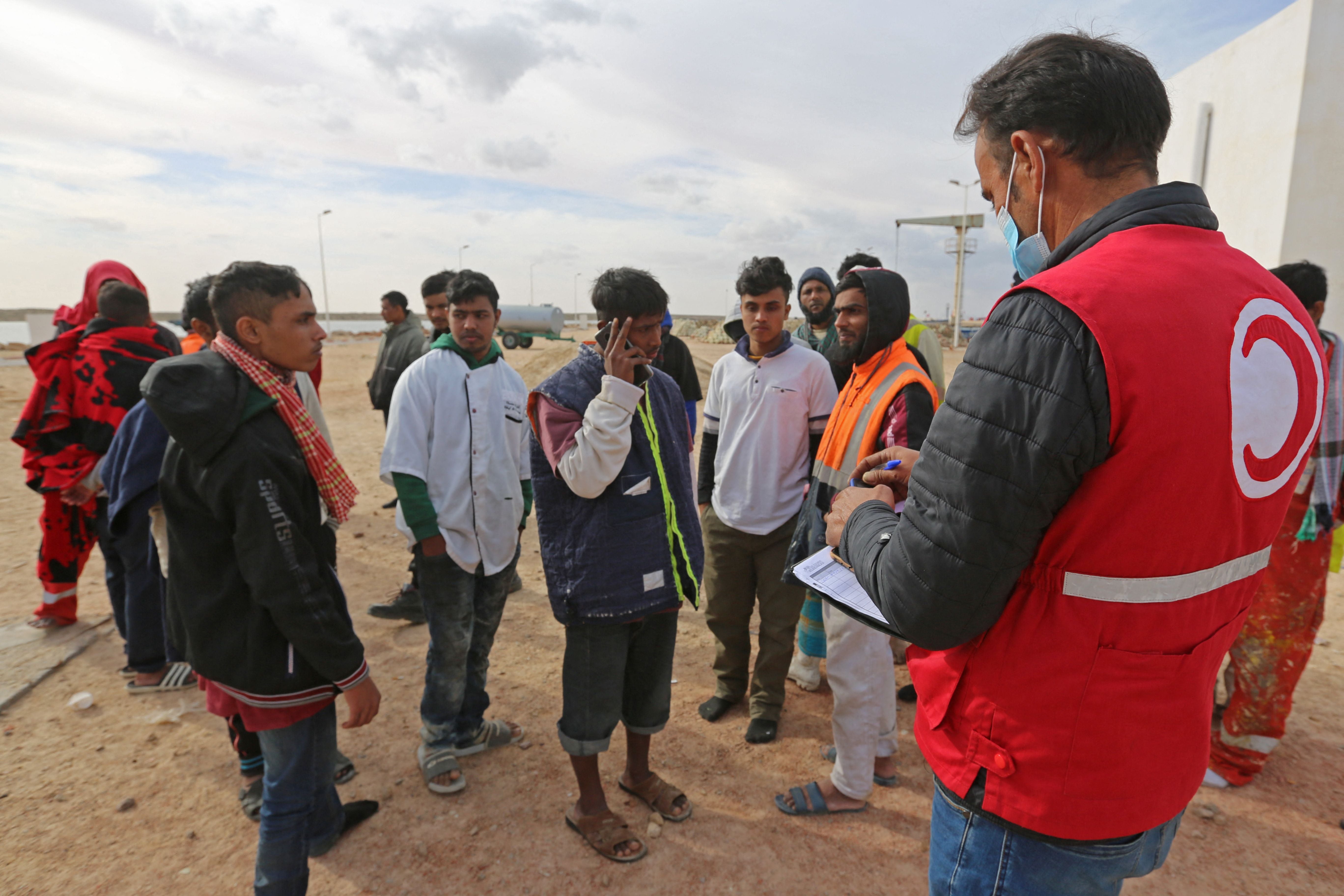 Migrants rescued by Tunisia’s national guard gather on the beach in Ben Guerdane, southern Tunisia, 6 January 2022