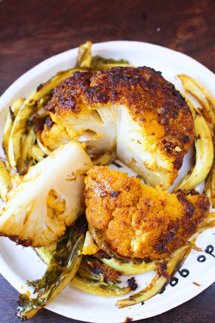 This cauliflower recipe calls for a harissa pesto, olive oil, maple syrup, ground cumin and turmeric mix