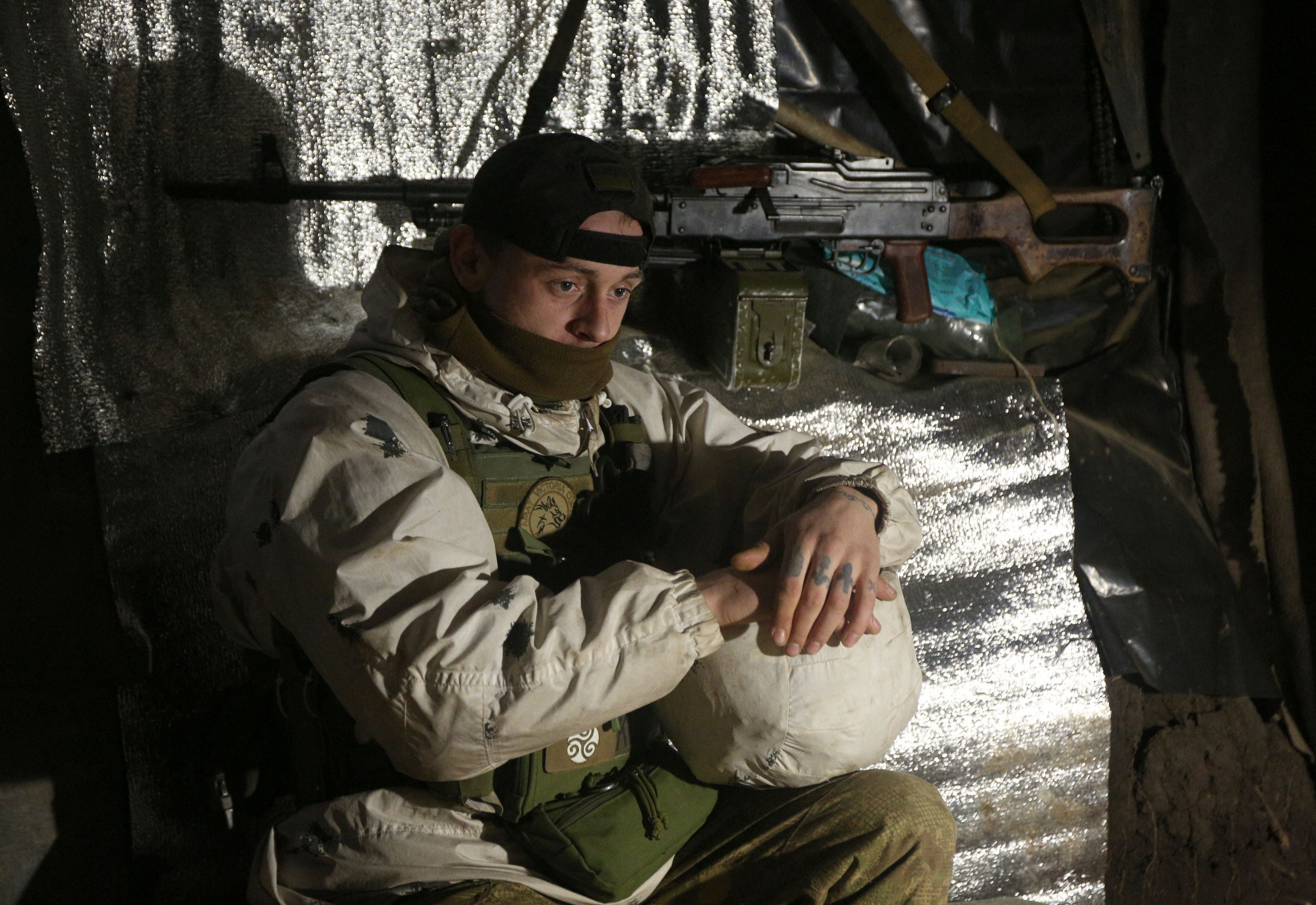 An Ukrainian Military Forces serviceman, looks on in a dugout on the frontline with Russia-backed separatists near Gorlivka, Donetsk region