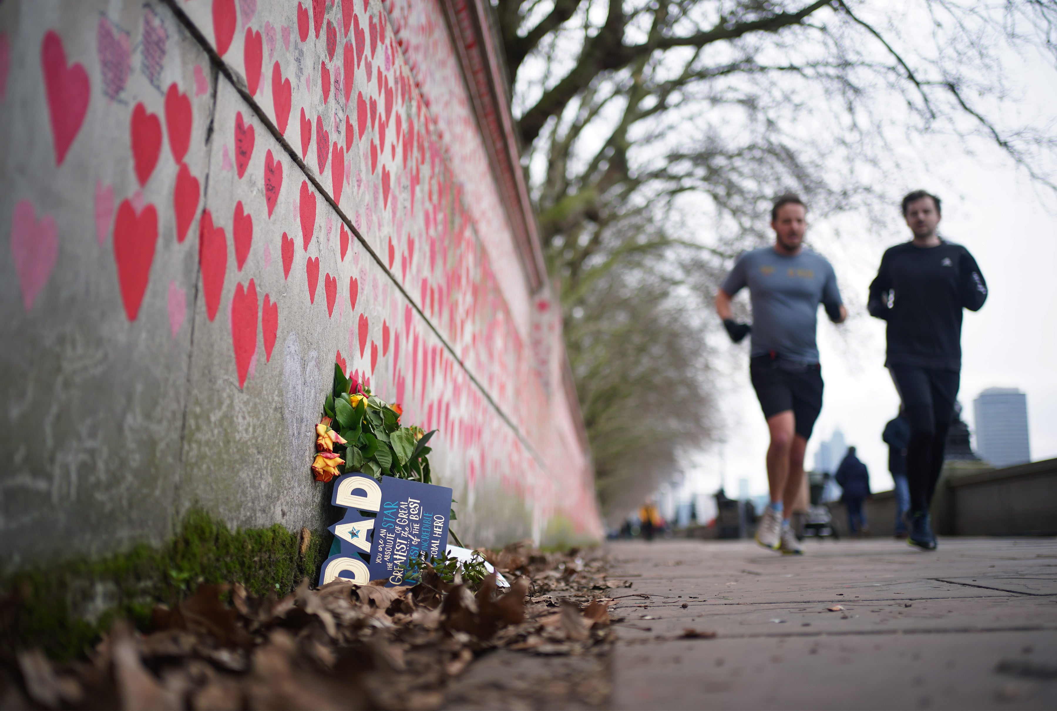 People jog past the Covid memorial wall near St Thomas’ Hospital in London (Yui Mok/PA)