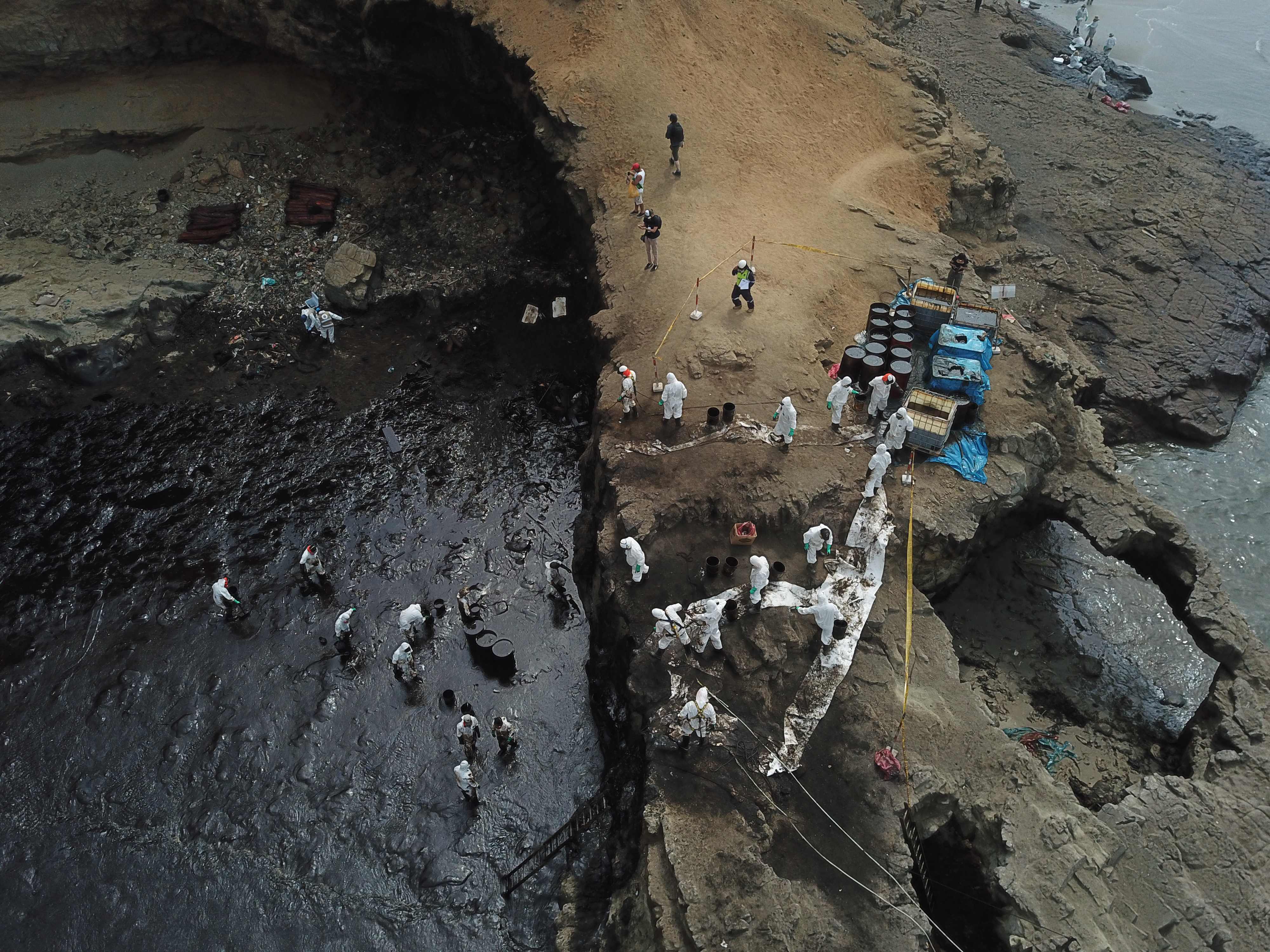 Aereal view of cleaning crews working to remove oil from a beach annexed to the summer resort town of Ancon, northern Lima