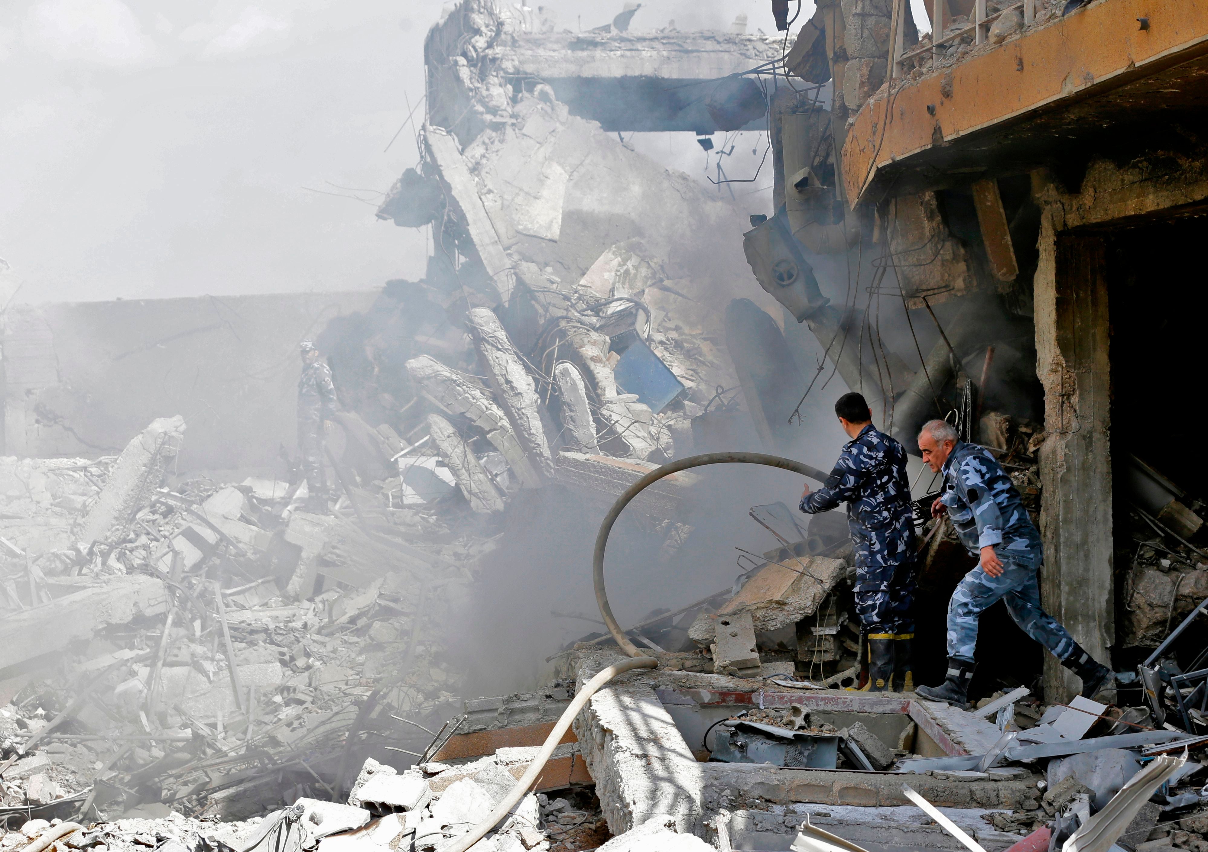 Syrian soldiers inspect the wreckage of a building described as part of the Scientific Studies and Research Centre, north of Damascus, following coalition airstrikes