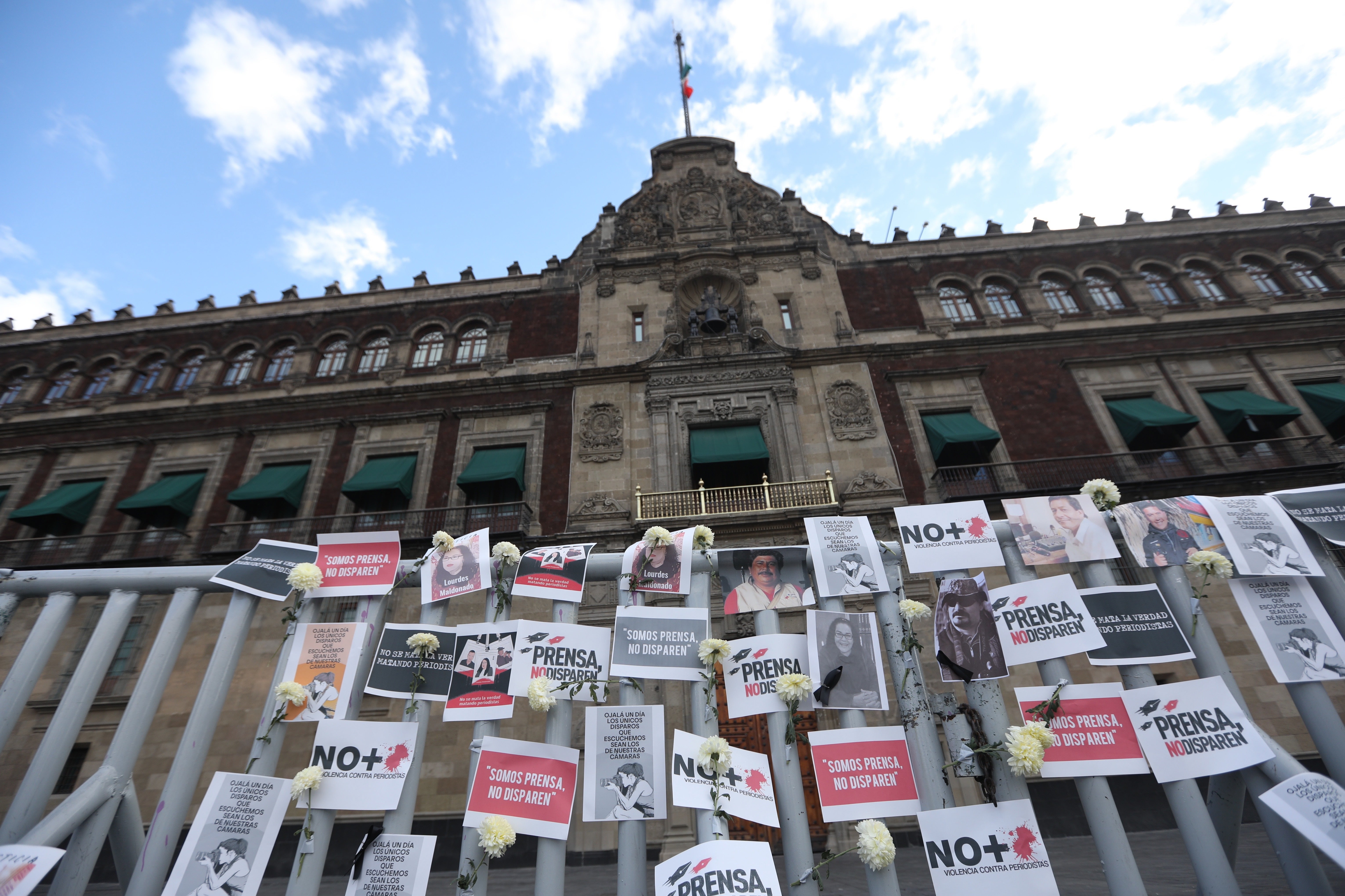 Posters, flowers, portraits and cameras outside the National Palace of Mexico City,