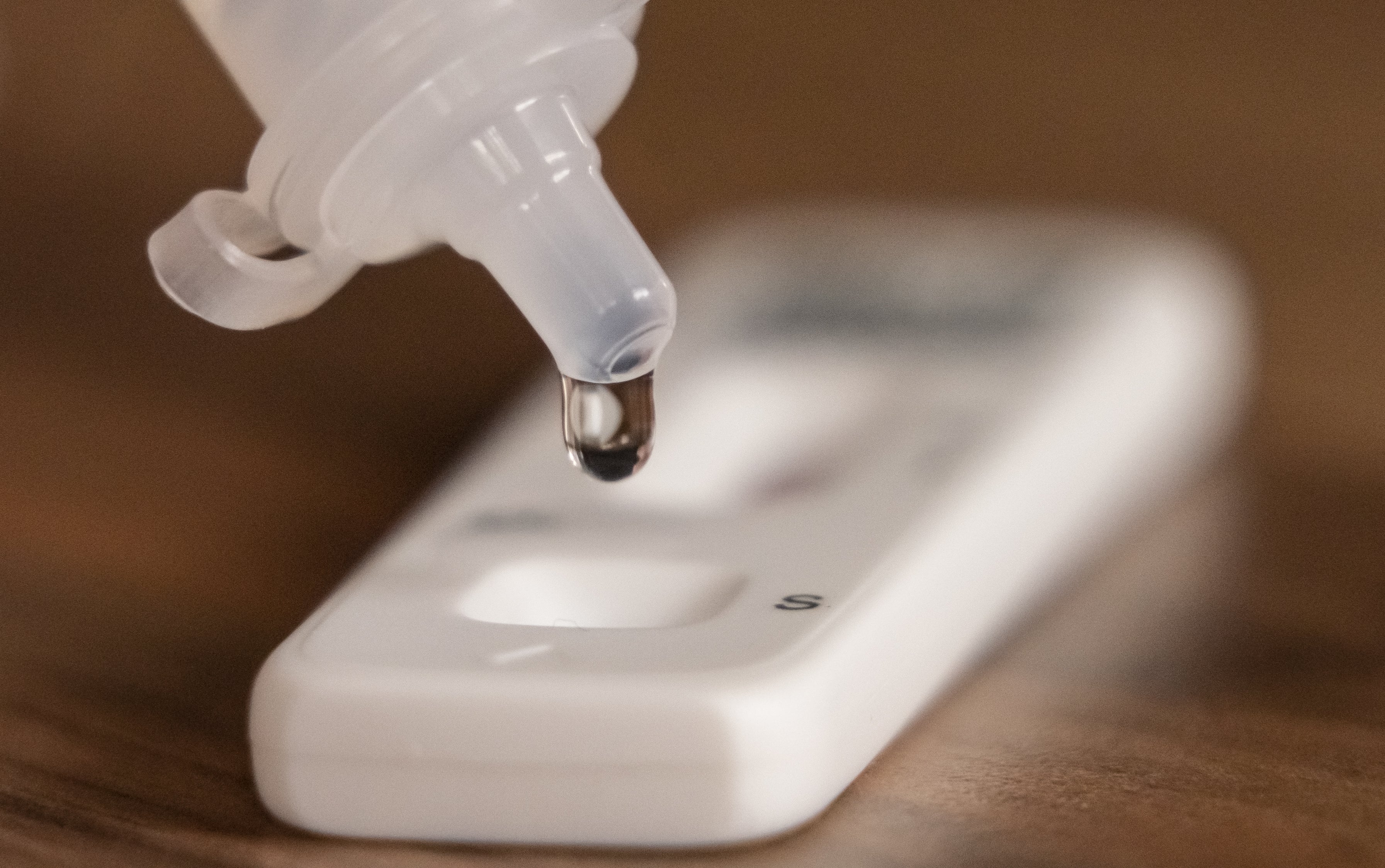 A person dripping testing solution into a Covid 19 lateral flow testing strip (Danny Lawson/PA)