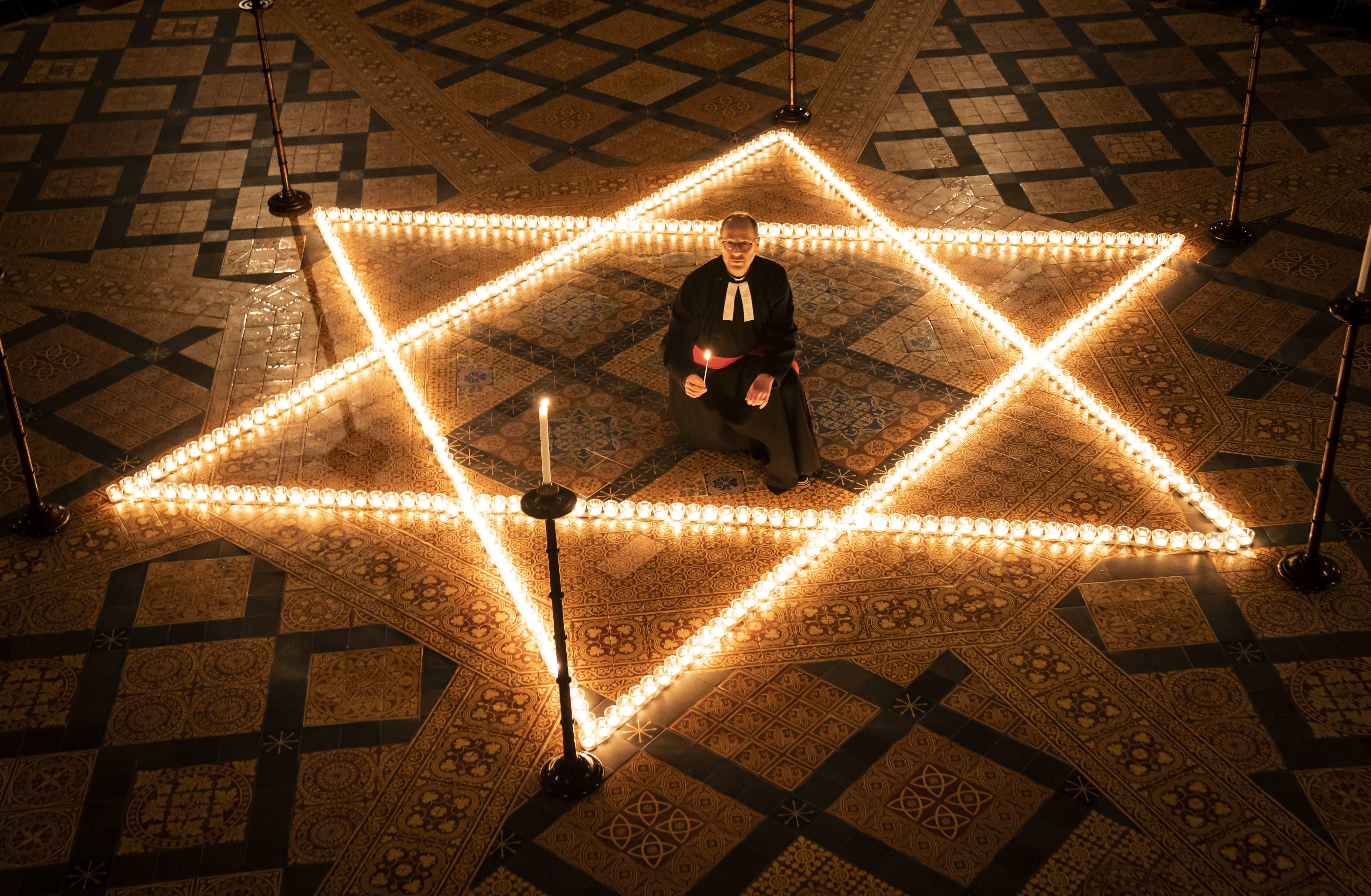 The Reverend Canon Michael Smith helps light six hundred candles in the shape of the Star of David (Danny Lawson/PA)