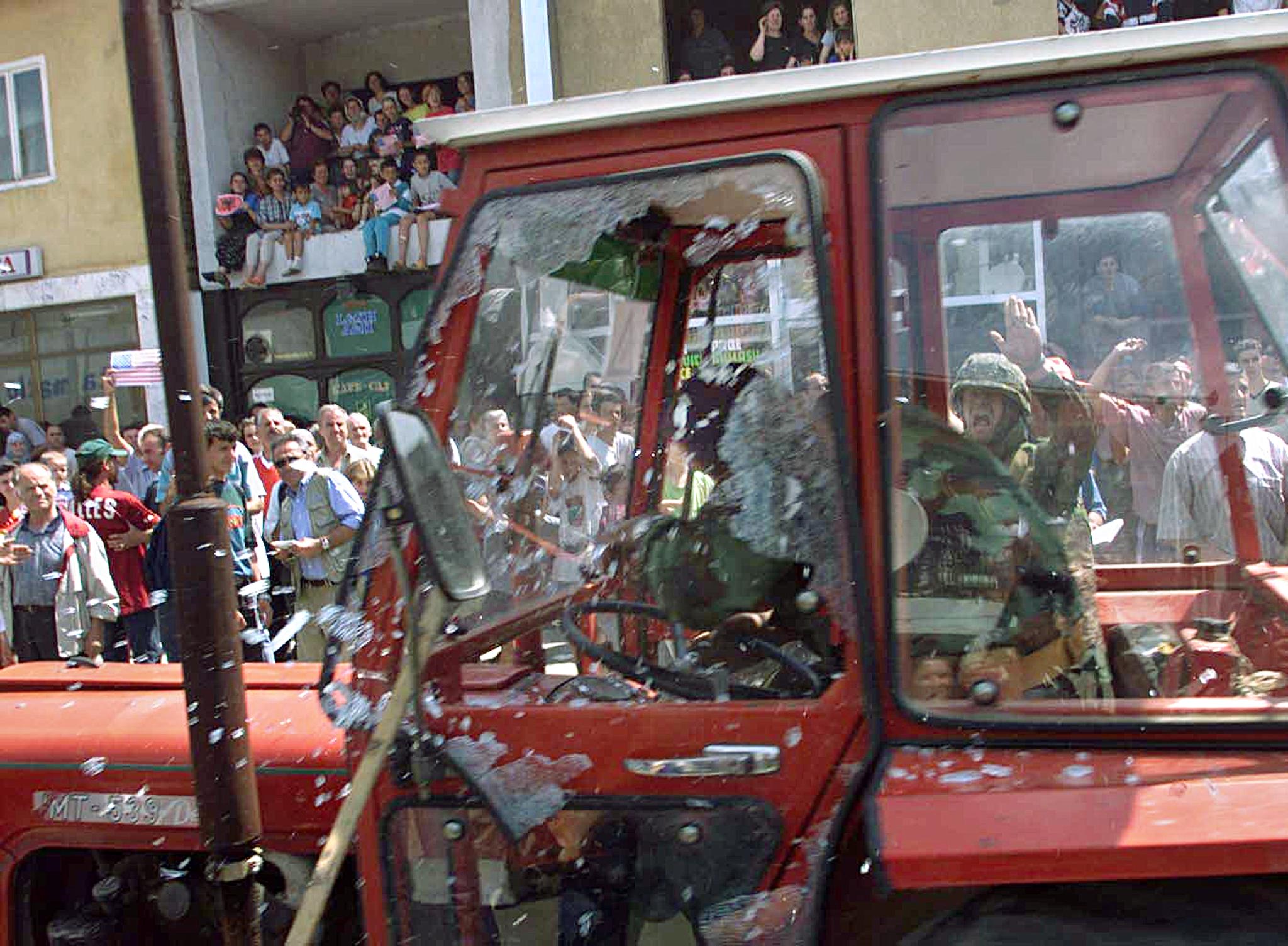 Angry Kosovars throw stones on a Serb resident leaving Prizren under the escort of German soldiers of the Nato-led KFOR, 13 June 1999