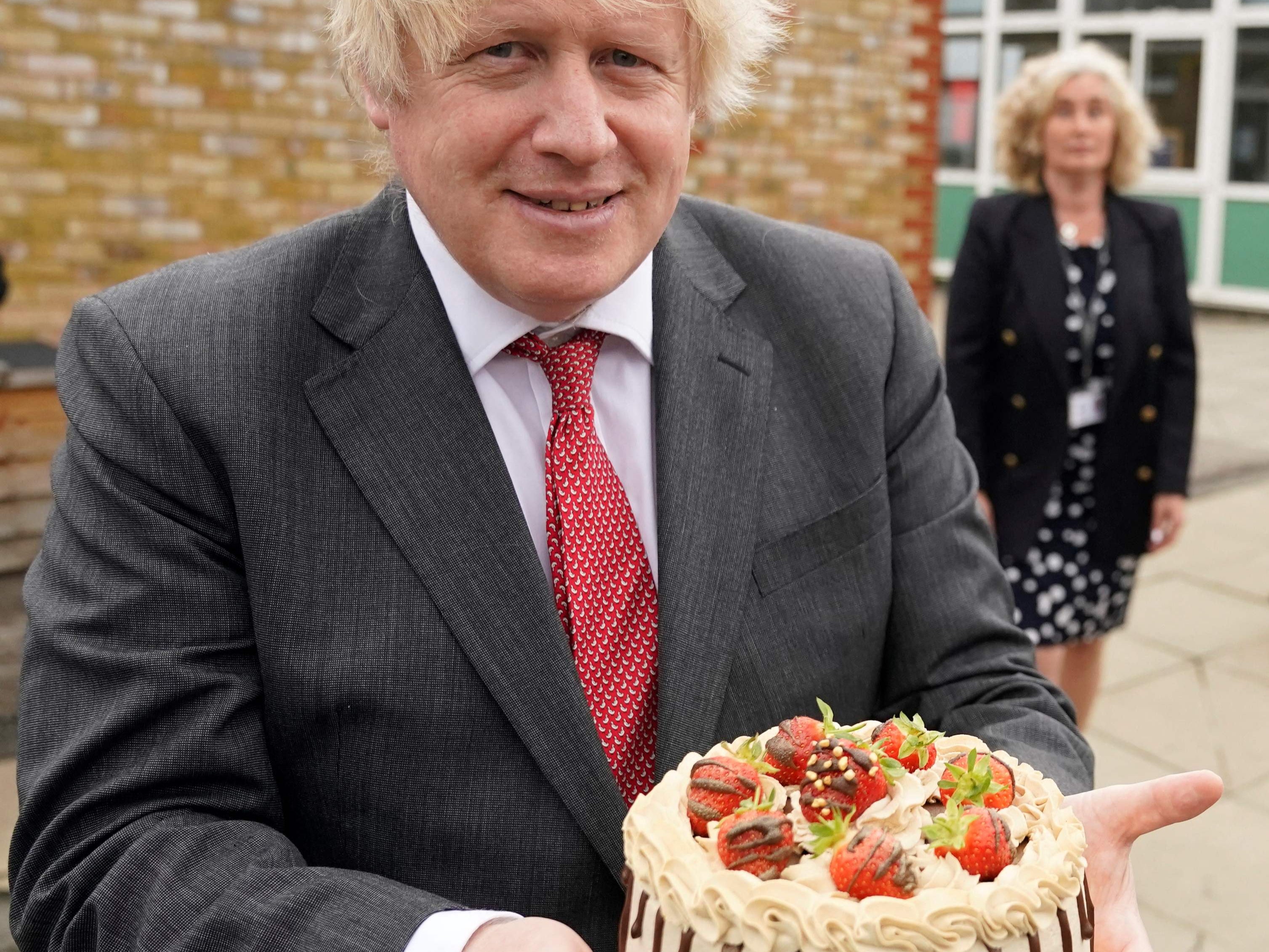 Boris Johnson holding a birthday cake presented to him by the staff during a socially distanced visit to Bovingdon Primary School