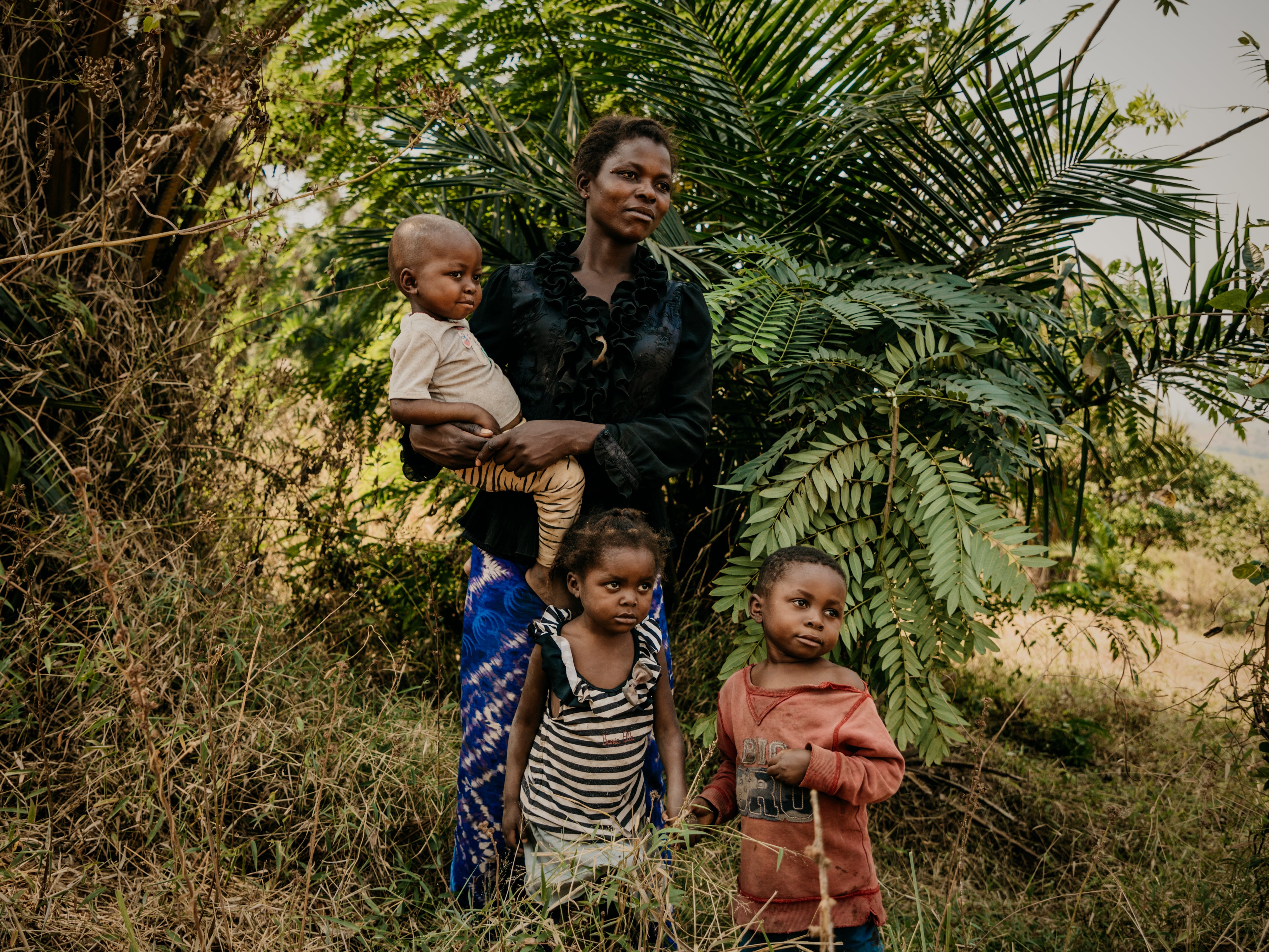 Mireille*, 29, poses for a portrait with her son Matisse*, 3 daughter Odette*, 5 and son Jules*,6 near their home