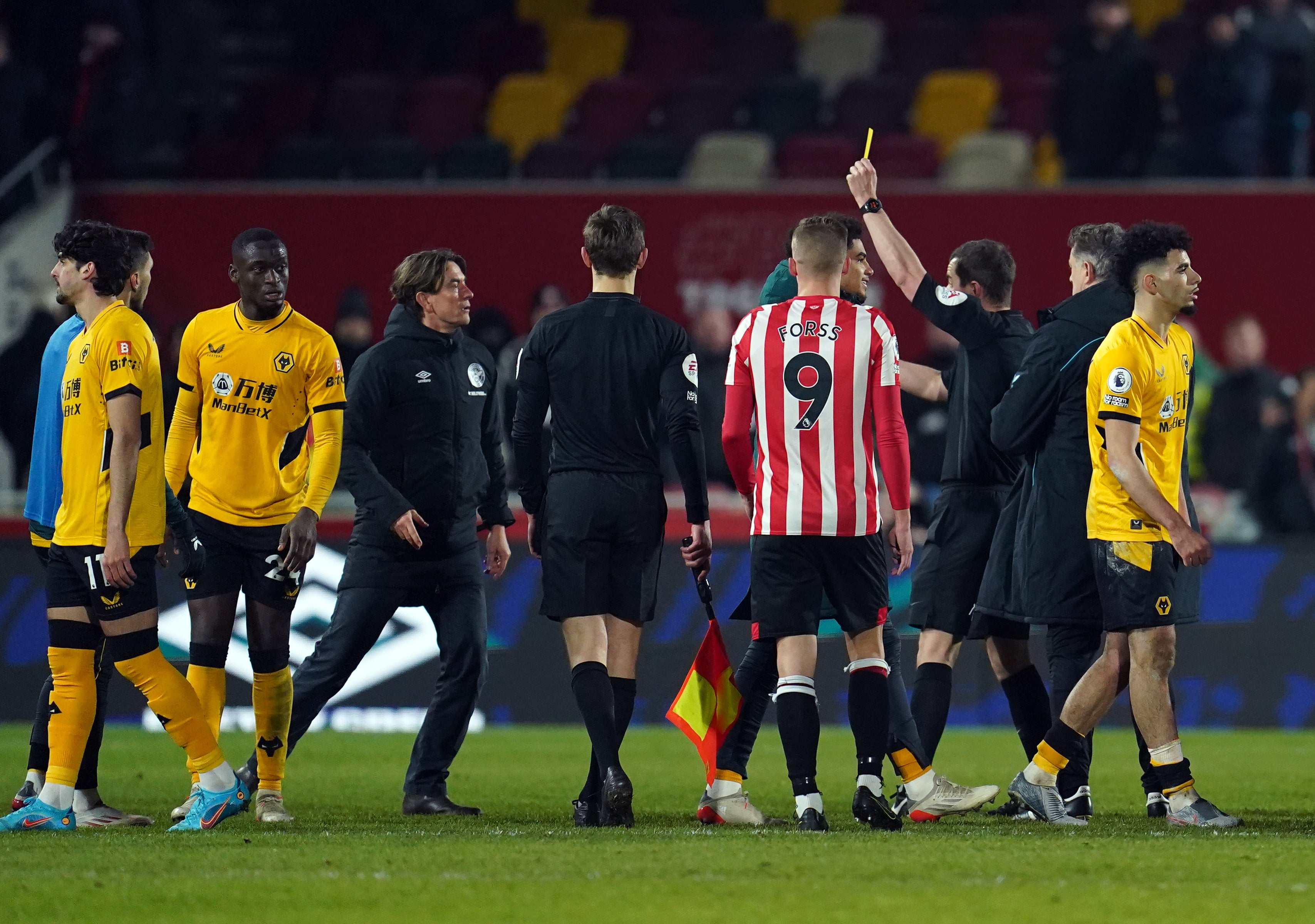 Thomas Frank, centre left, receives his first yellow card from referee Peter Bankes (Nick Potts/PA)