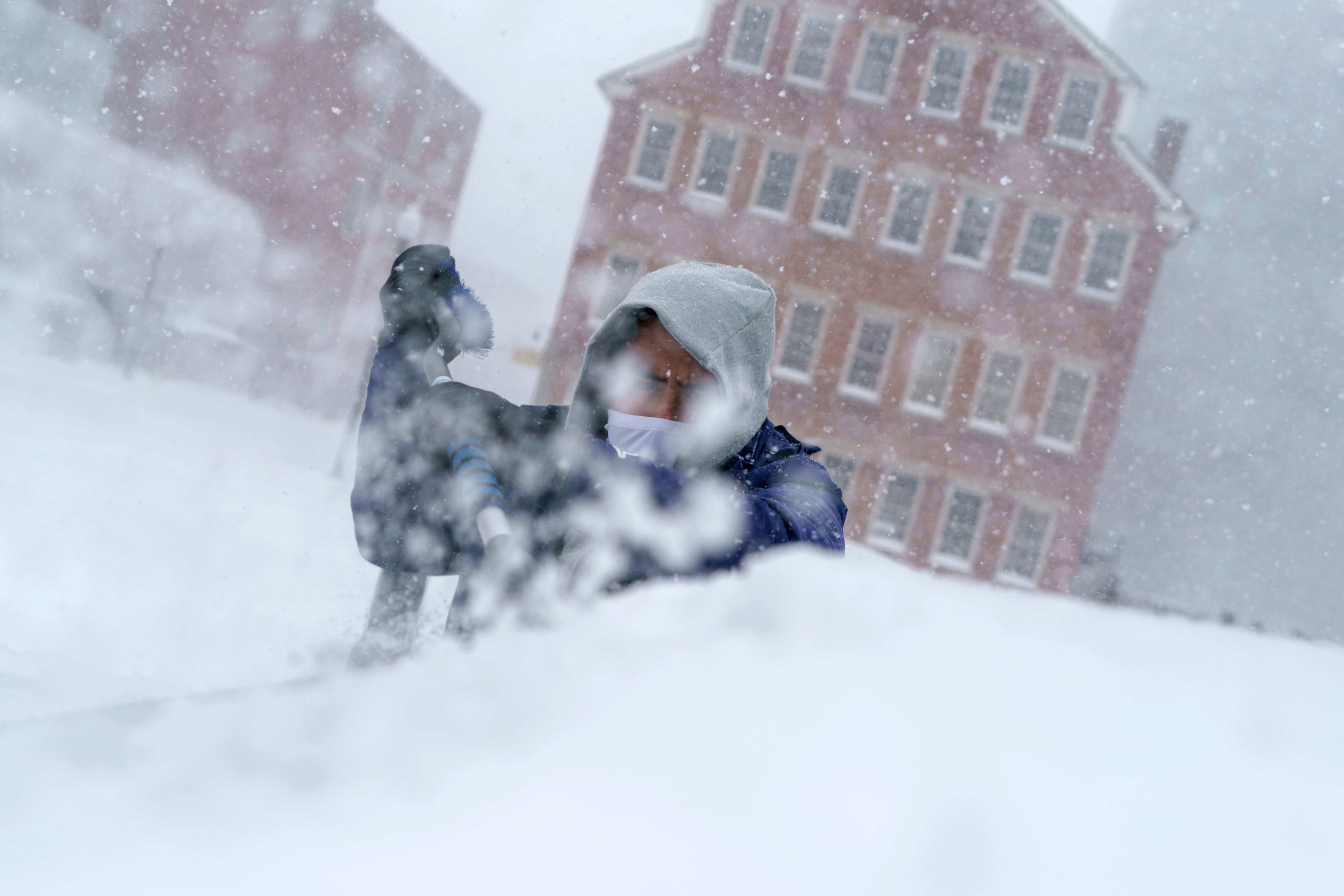Xavier Martinez scrapes snow off his windshield during a storm in Providence, RI on 29 January 2022