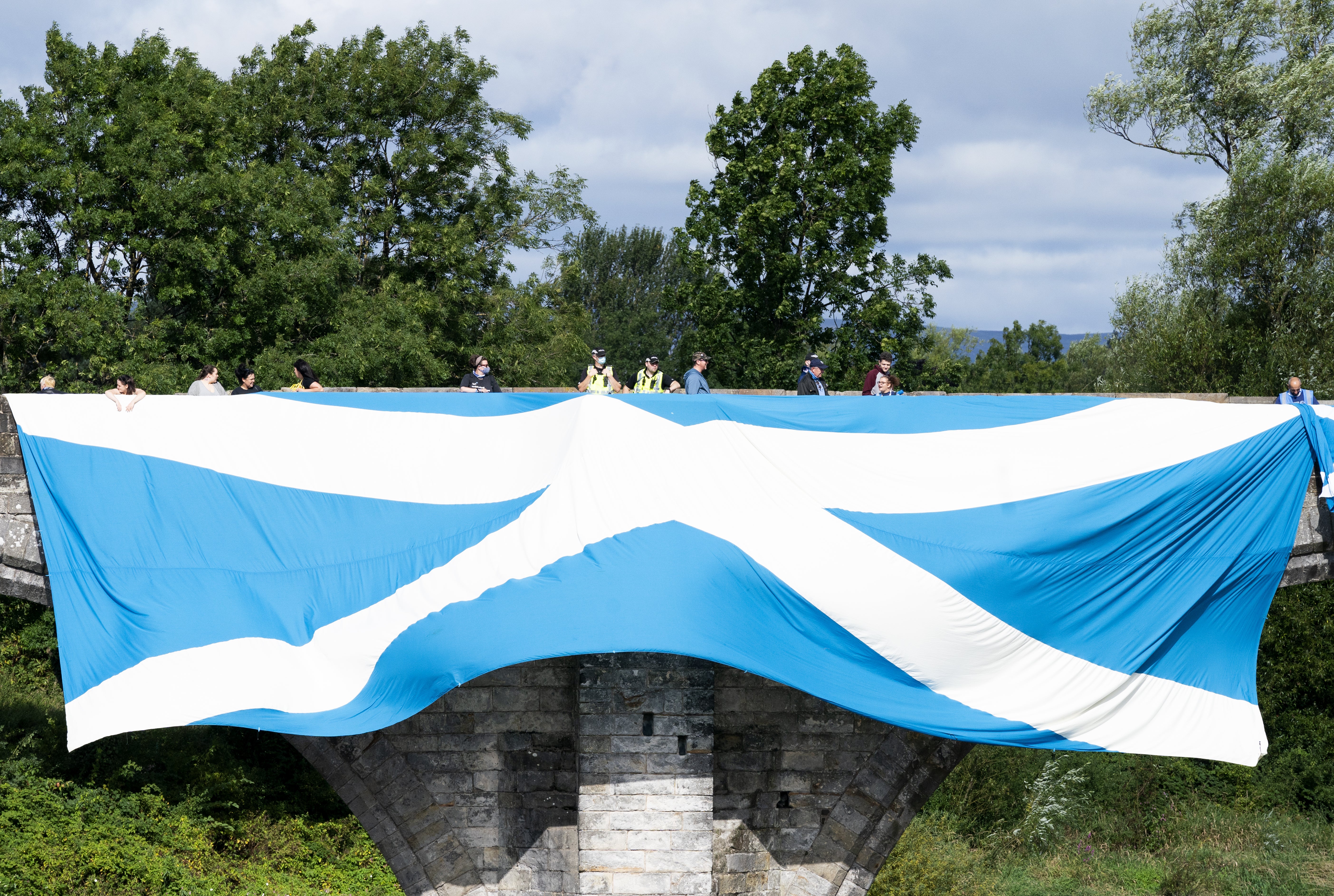 Supporters of Scottish independence hang a huge Saltire flag over the Auld Brig (Jane Barlow/PA)