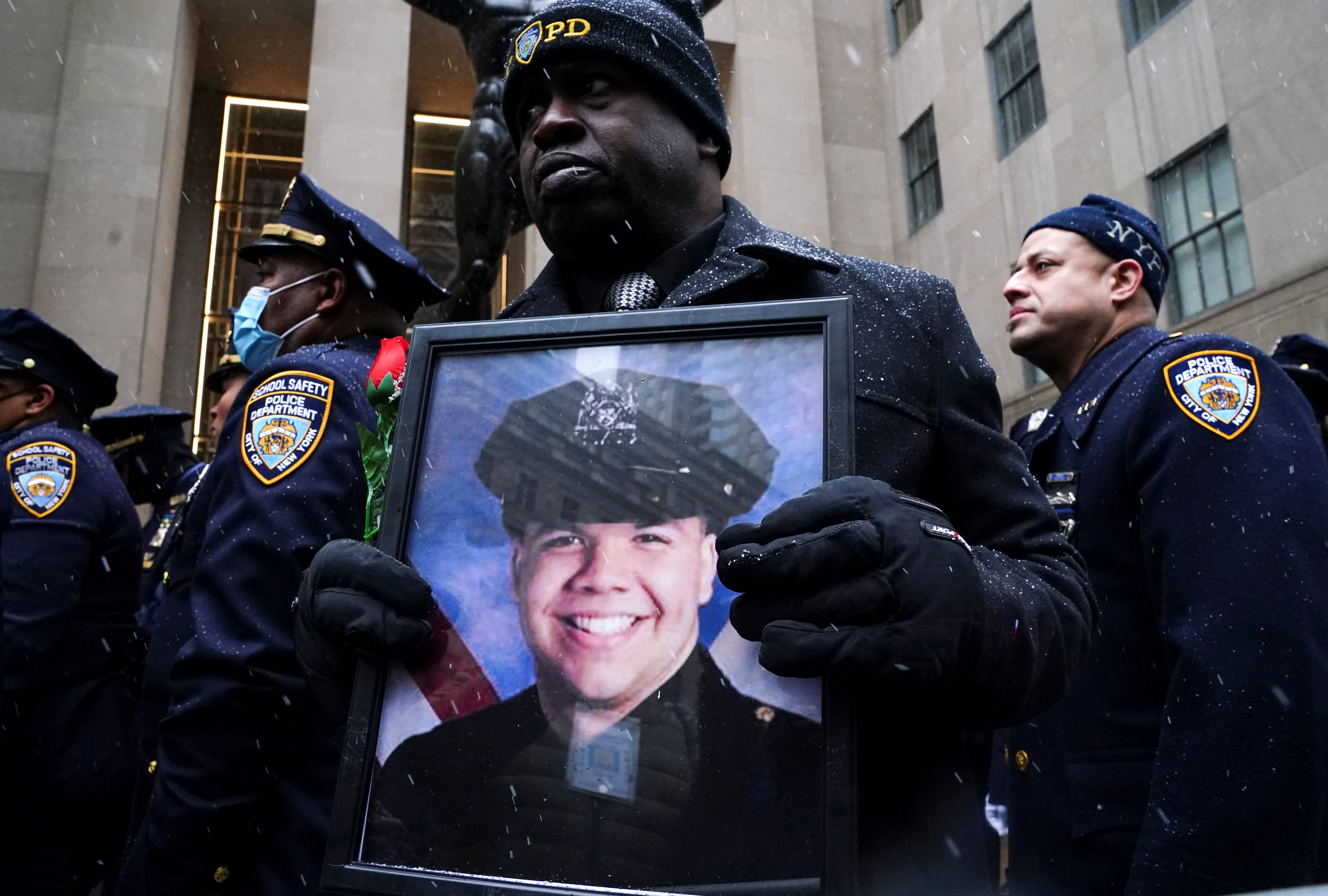 Calvin Hunt holds a picture of NYPD officer Jason Rivera, who was fatally shot in Harlem in January.