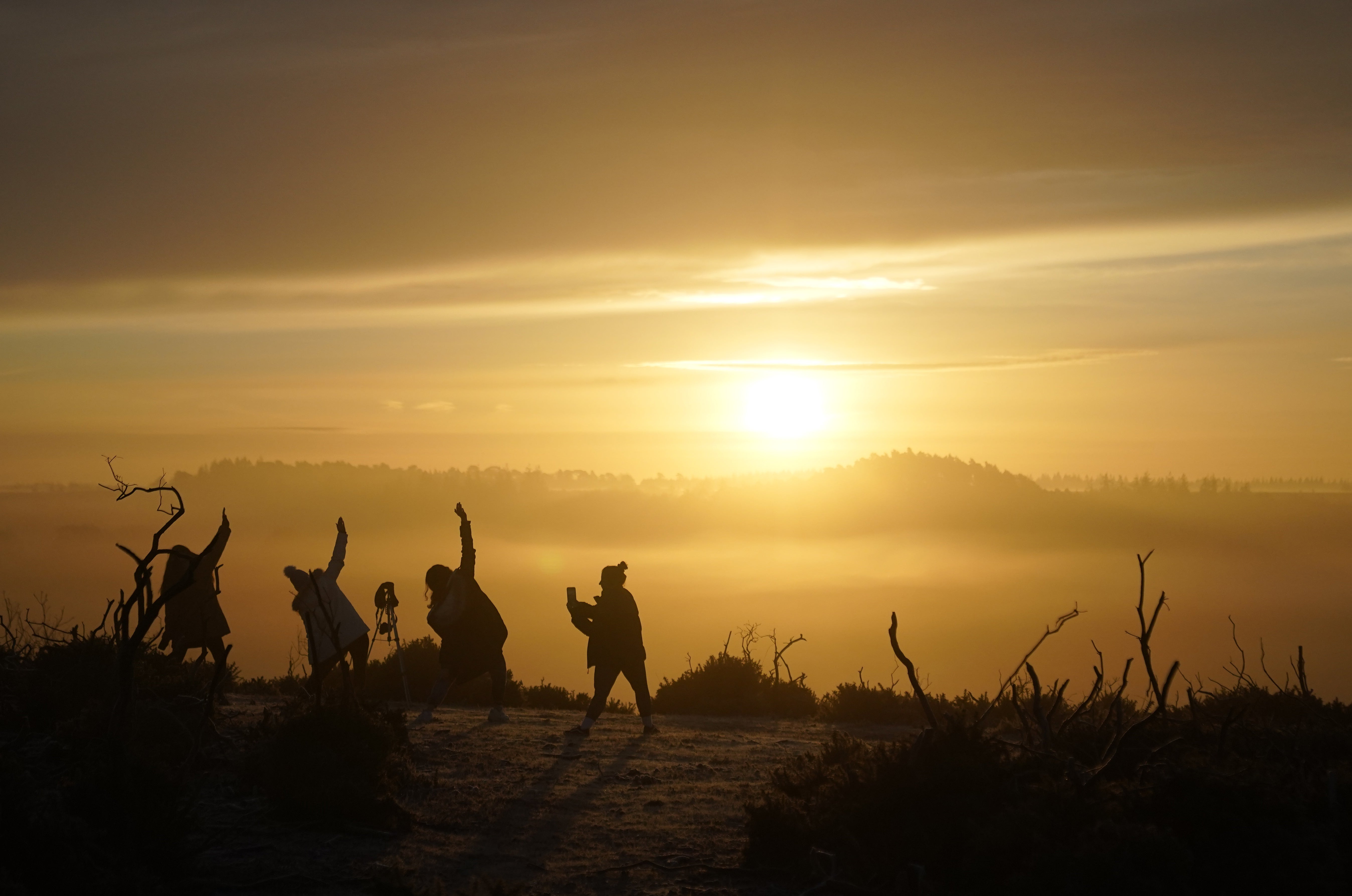 People practise yoga as the sun rises near Fordingbridge in the New Forest, Hampshire (Andrew Matthews/PA)