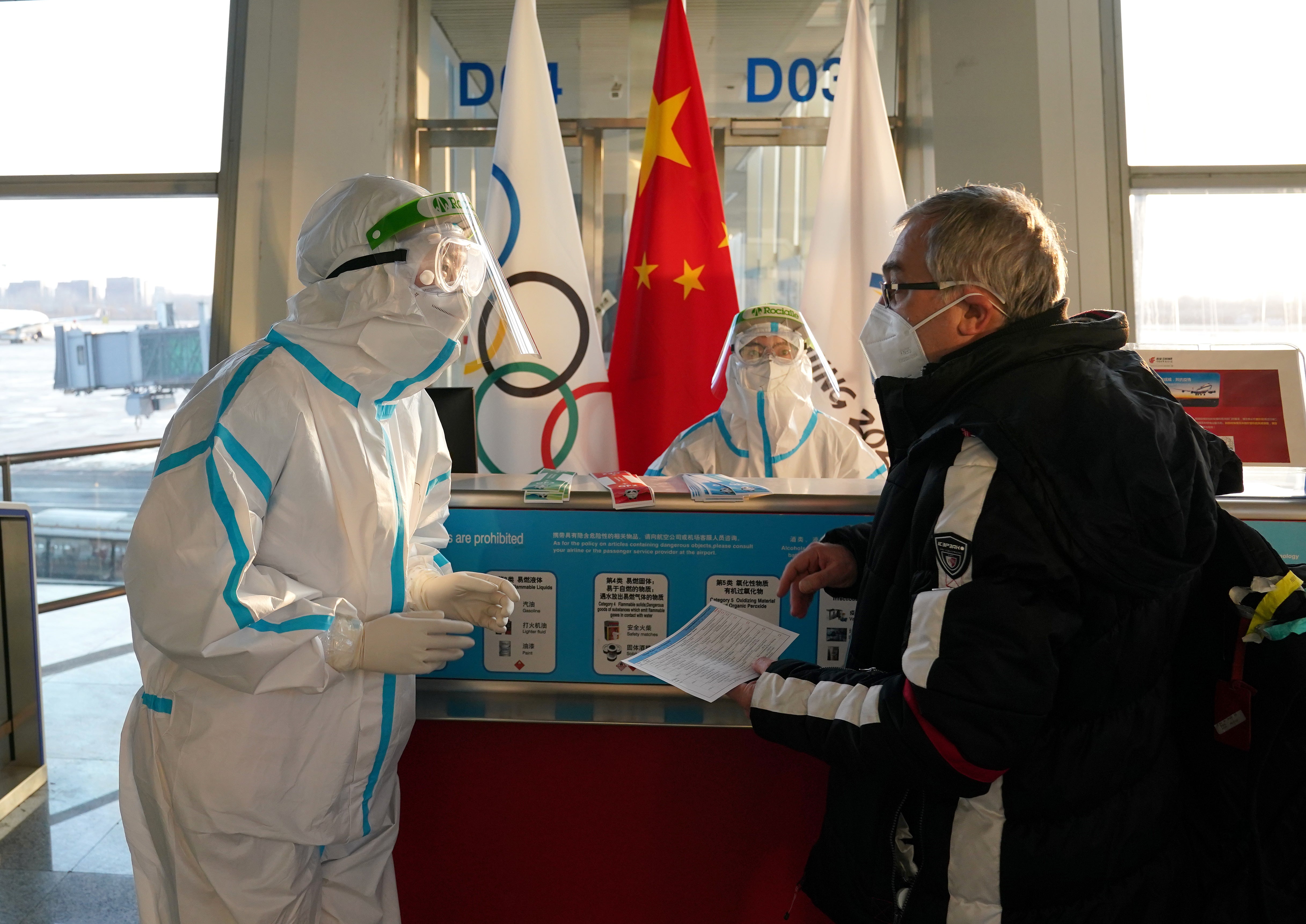 Airport staff wearing hazmat suits assist passengers at Beijing International Airport (Andrew Milligan/PA)