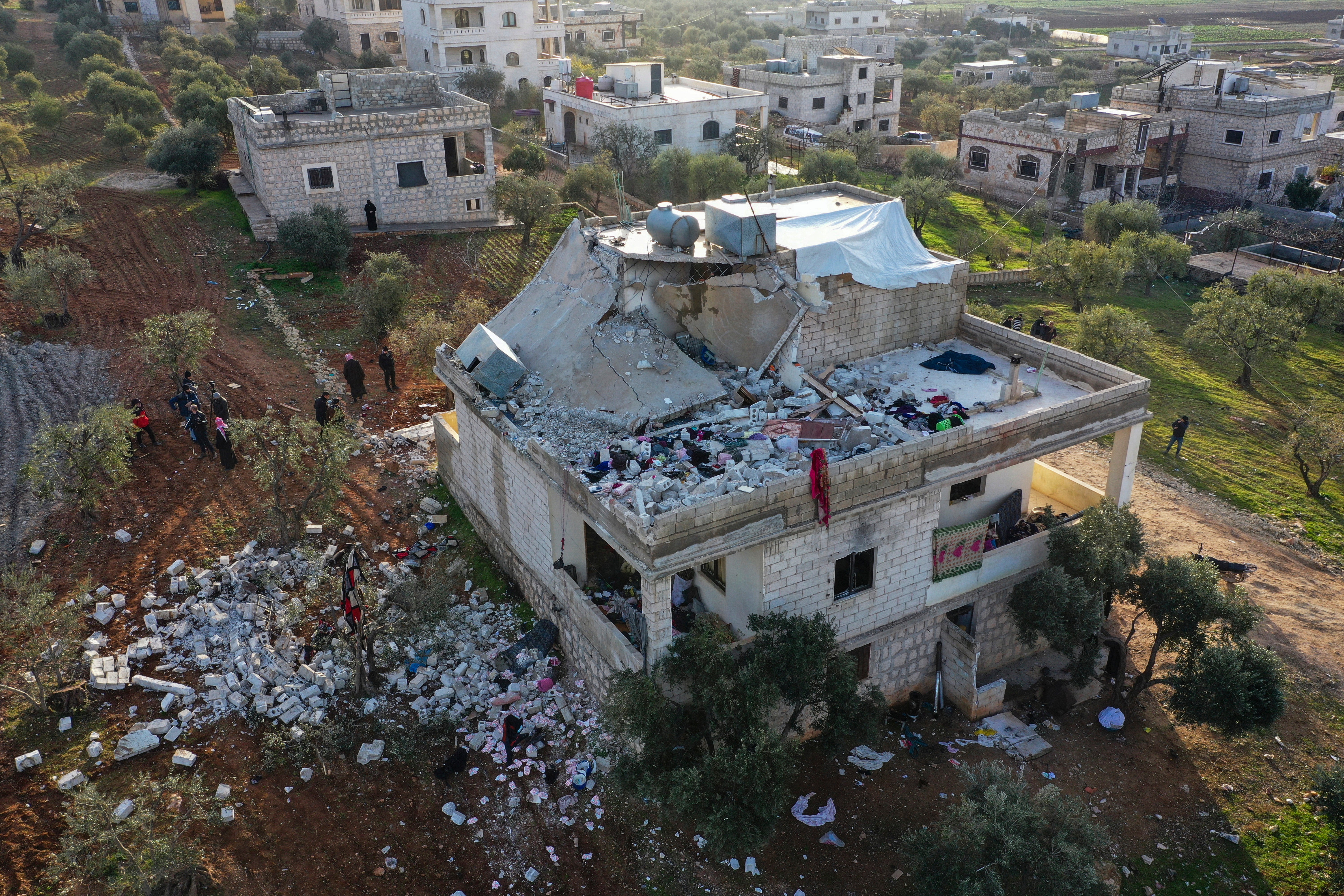 People inspect a destroyed house following an operation by the U.S. military in the Syrian village of Atmeh, in Idlib province, Syria, Thursday, Feb. 3, 2022